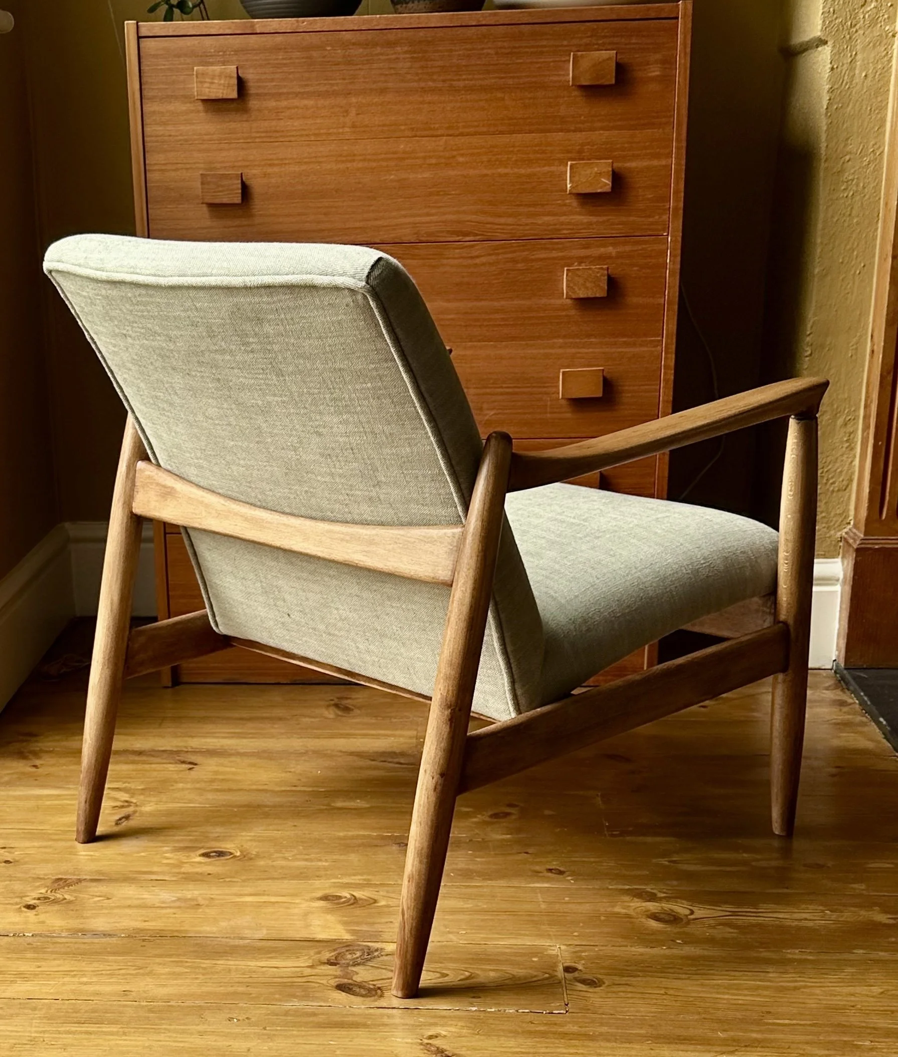 Mid-century Edmund Homa armchair with light green linen upholstery, wooden armrests and tapered legs.