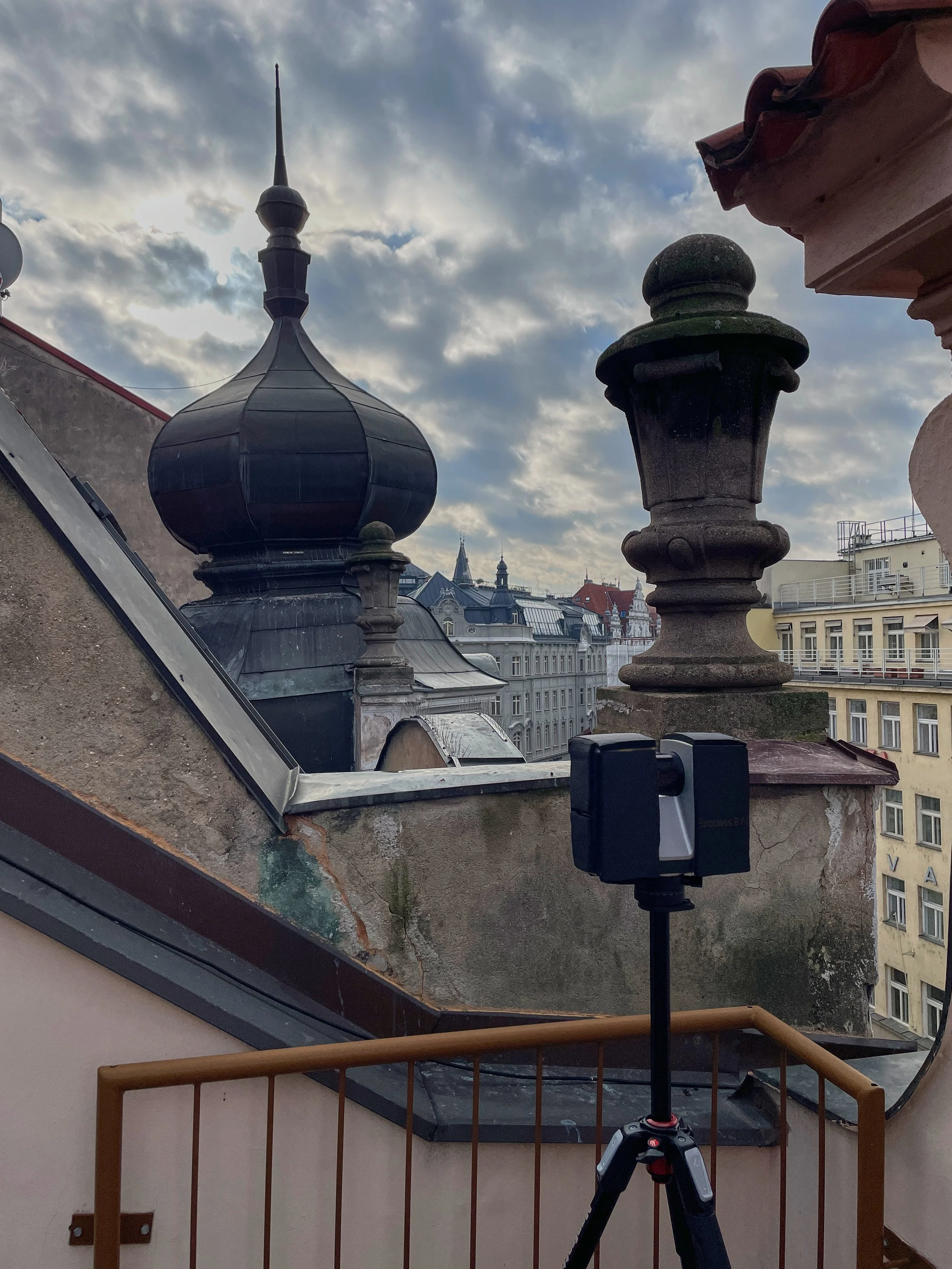 Laserovy skener pri zamerovani strechy s vyhledem na historicke centrum Prahy