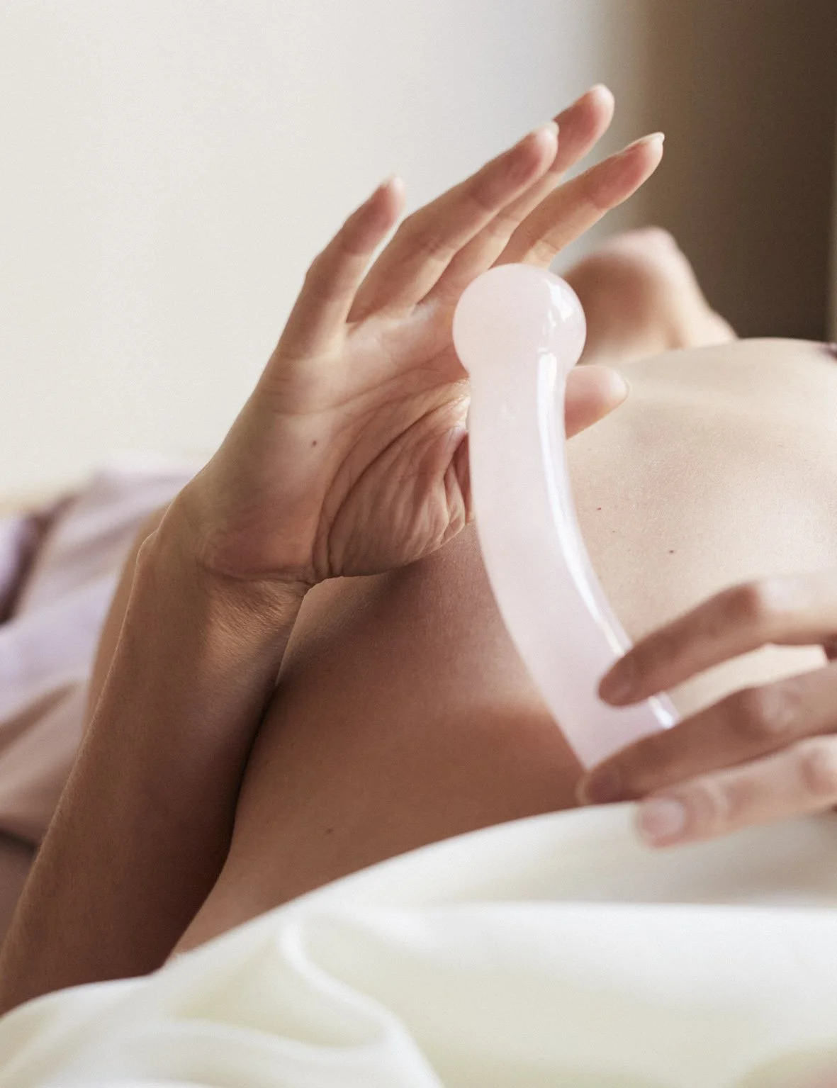 Close-up of a person's hand touching their chest with a clear glass object resting on the skin.