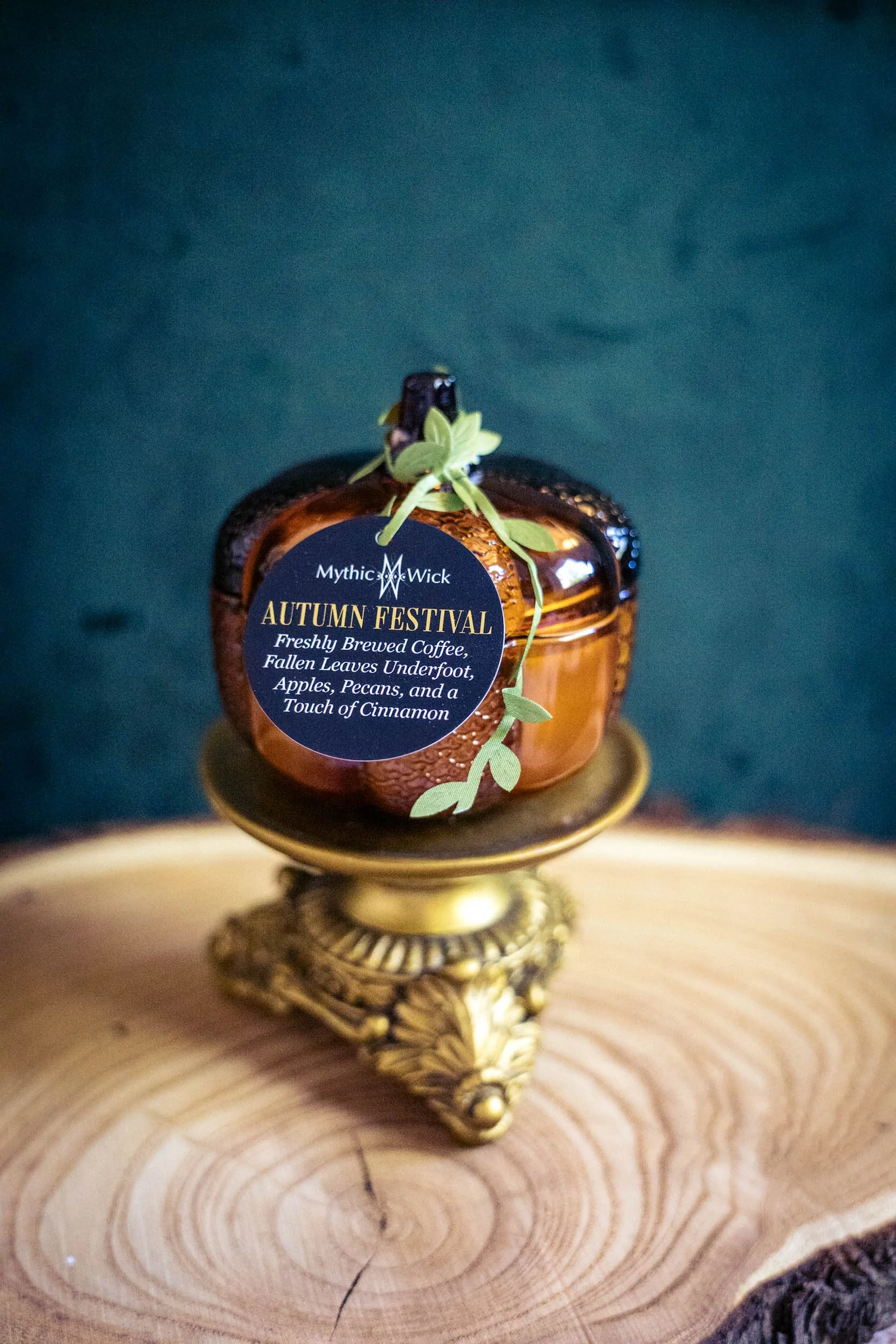 an amber glass pumpkin shaped jar candle with a tag that reads "autumn festival"