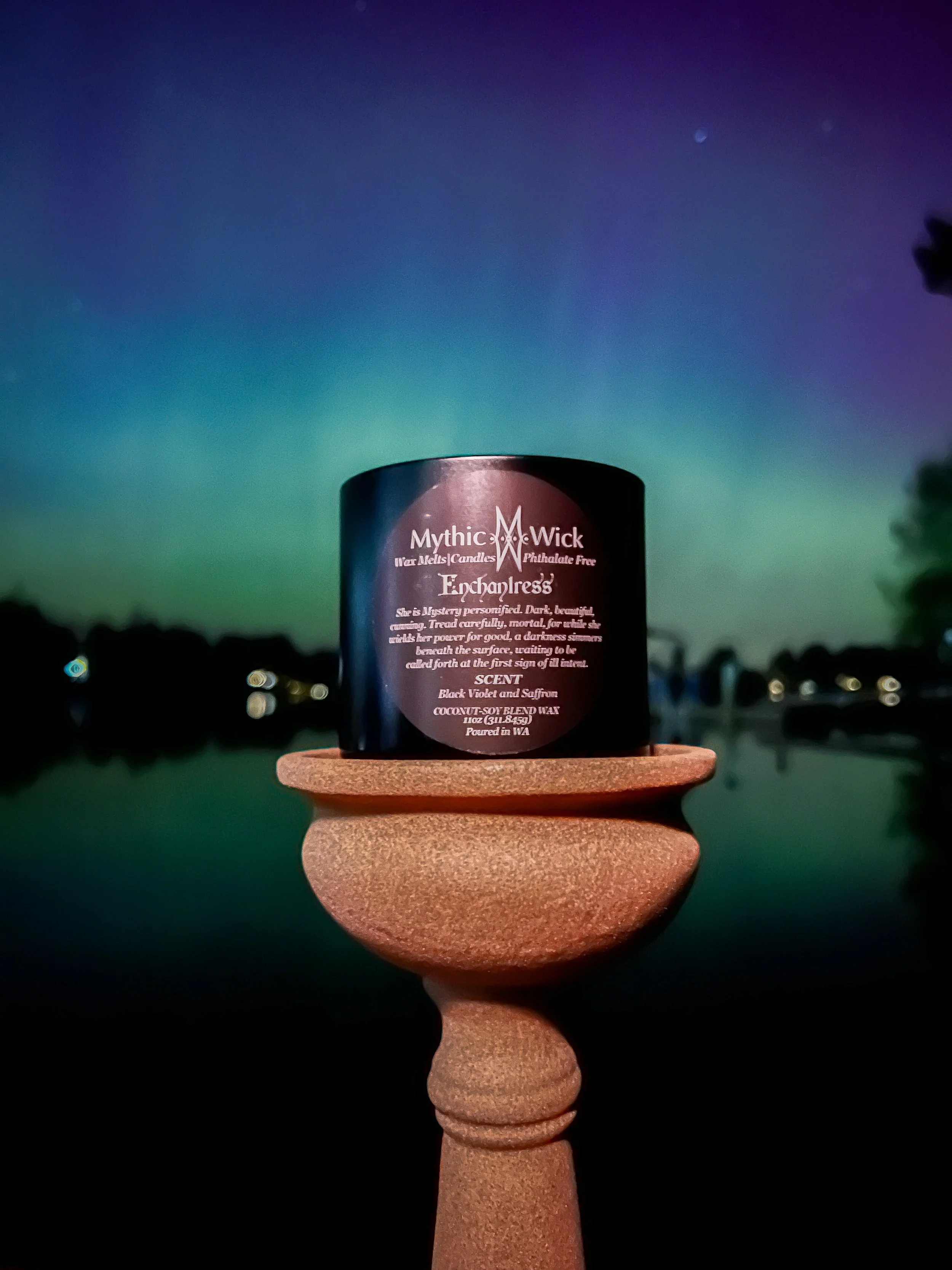 A black candle against a backdrop of the Northern Lights