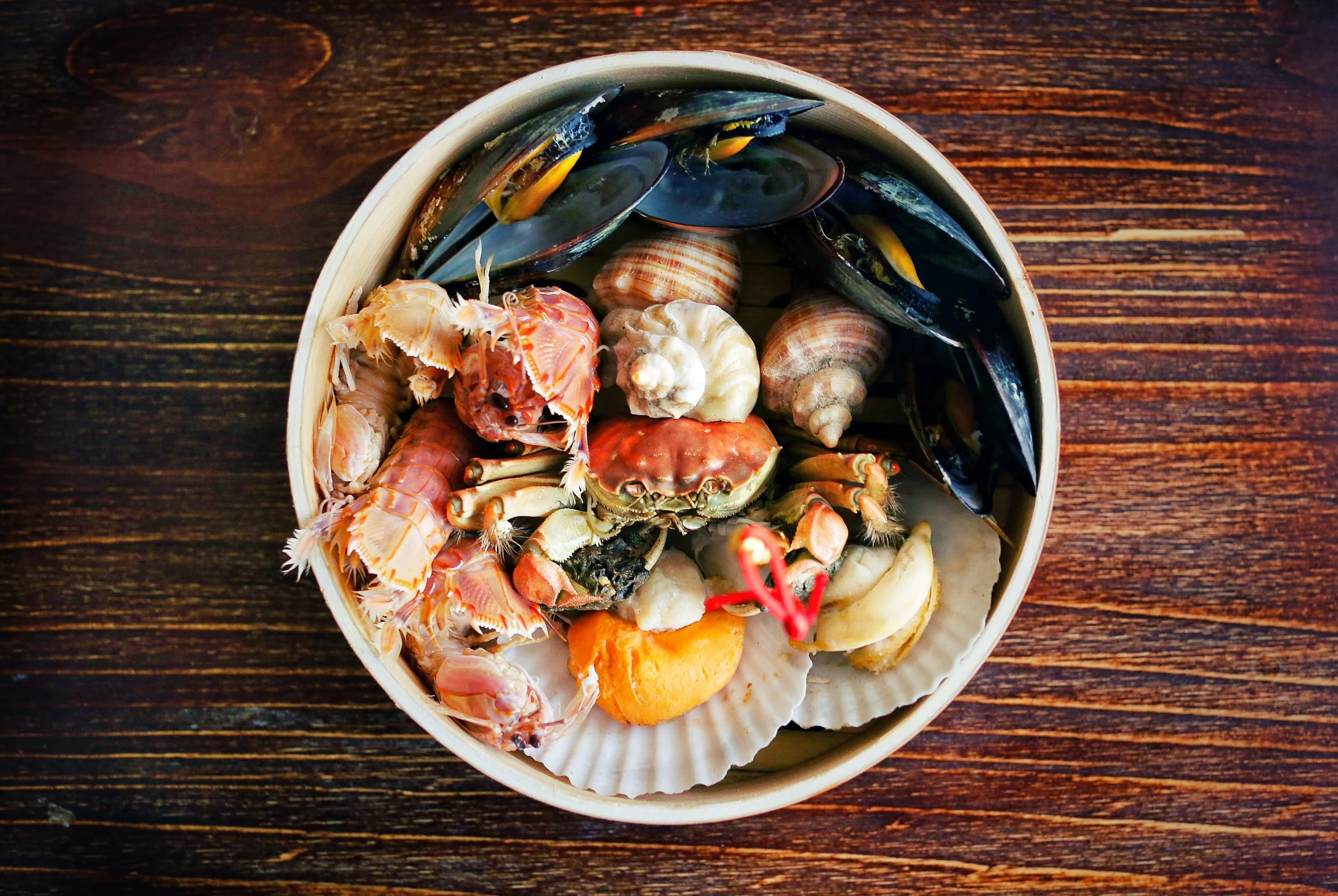 a white bowl filled with seafood, such as crab, clams, lobster, mussels, and shells