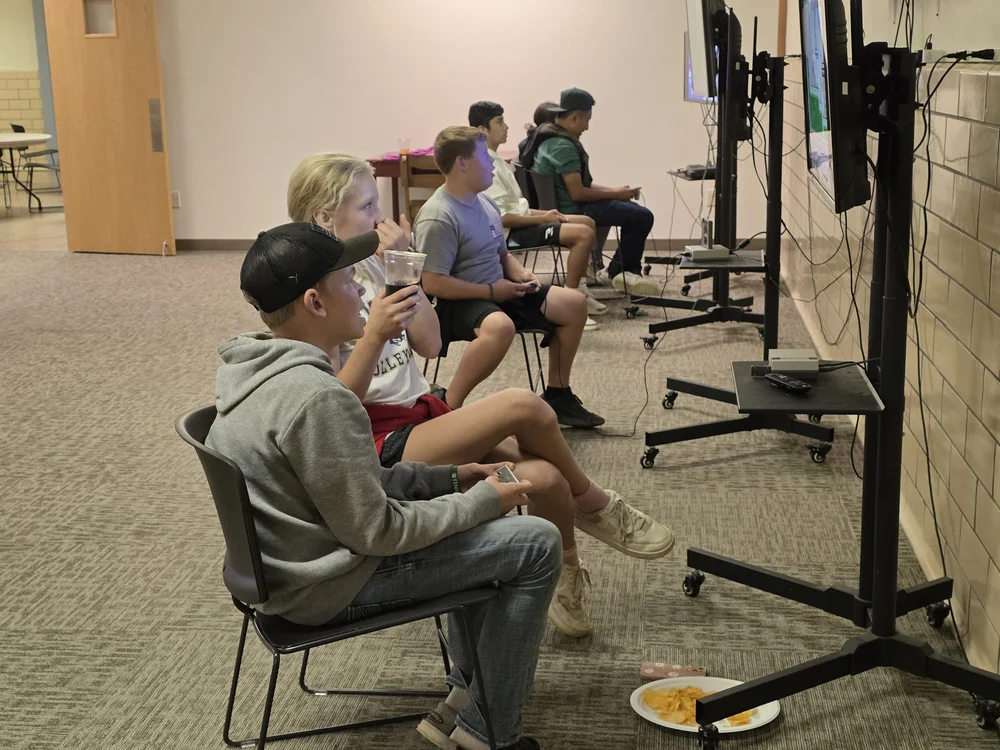 Students eating snacks and playing video games in the church basement