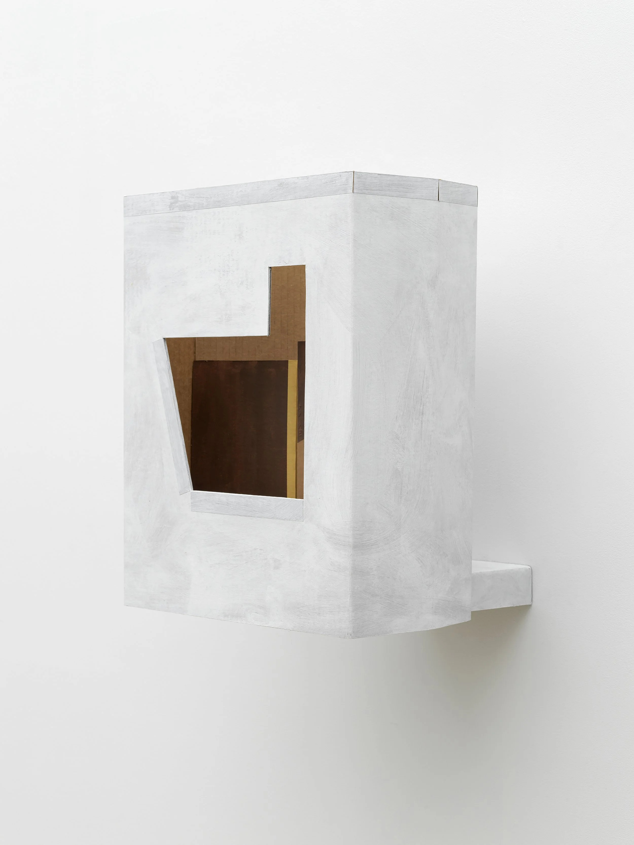 A white architectural model with a cutout window, placed on a white surface against a white background.