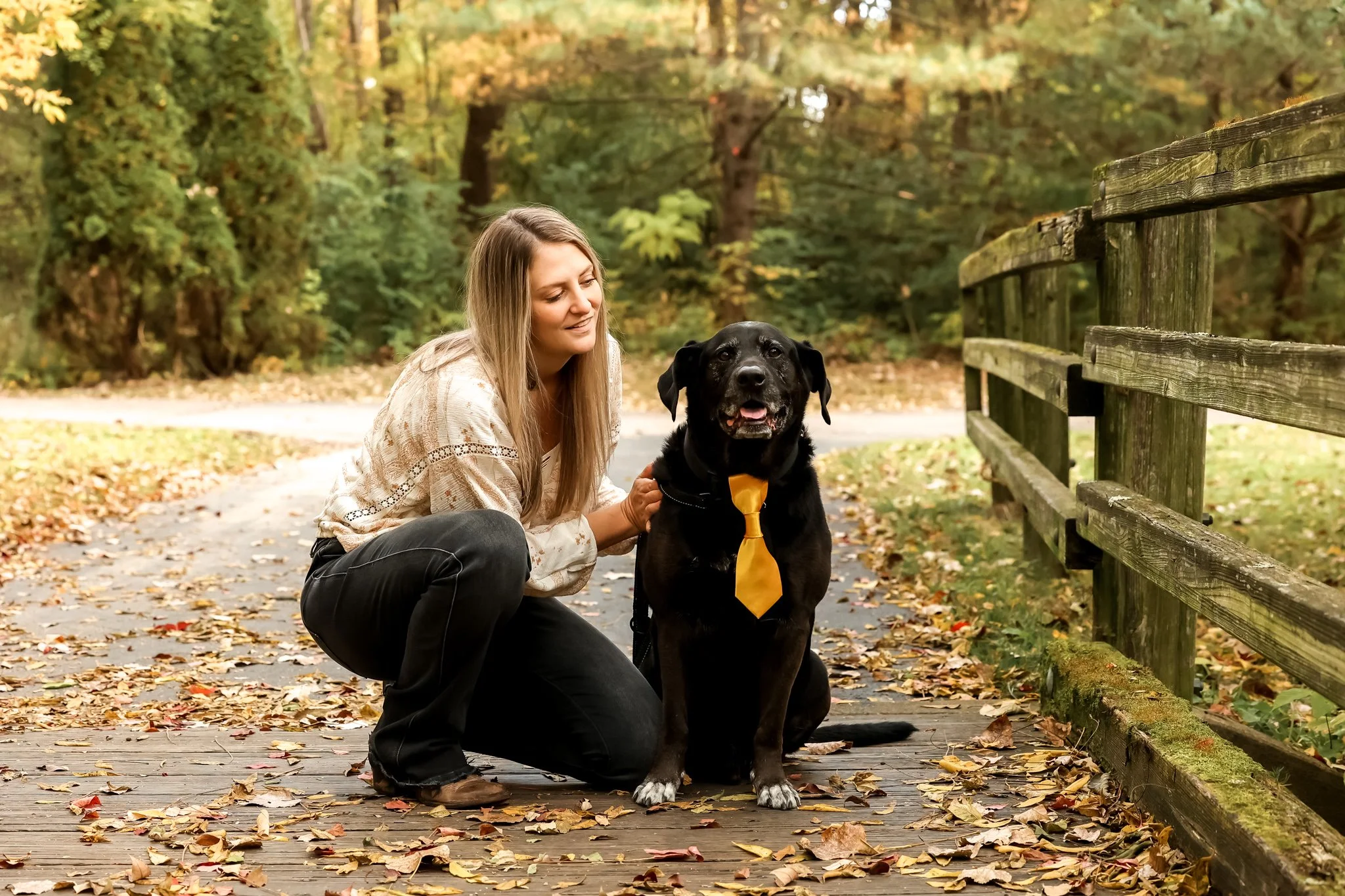 Caitlin and her dog dog Shadoe who is wearing a handmade golden yellow bowtie in a park