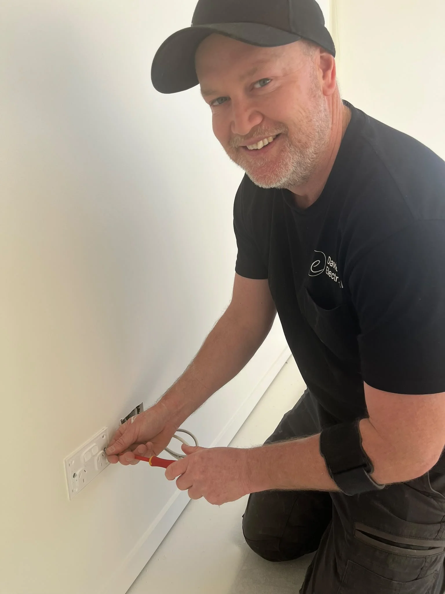 Tony from Davies Electrical works on a new-build power outlet, plugging in and testing a power cord
