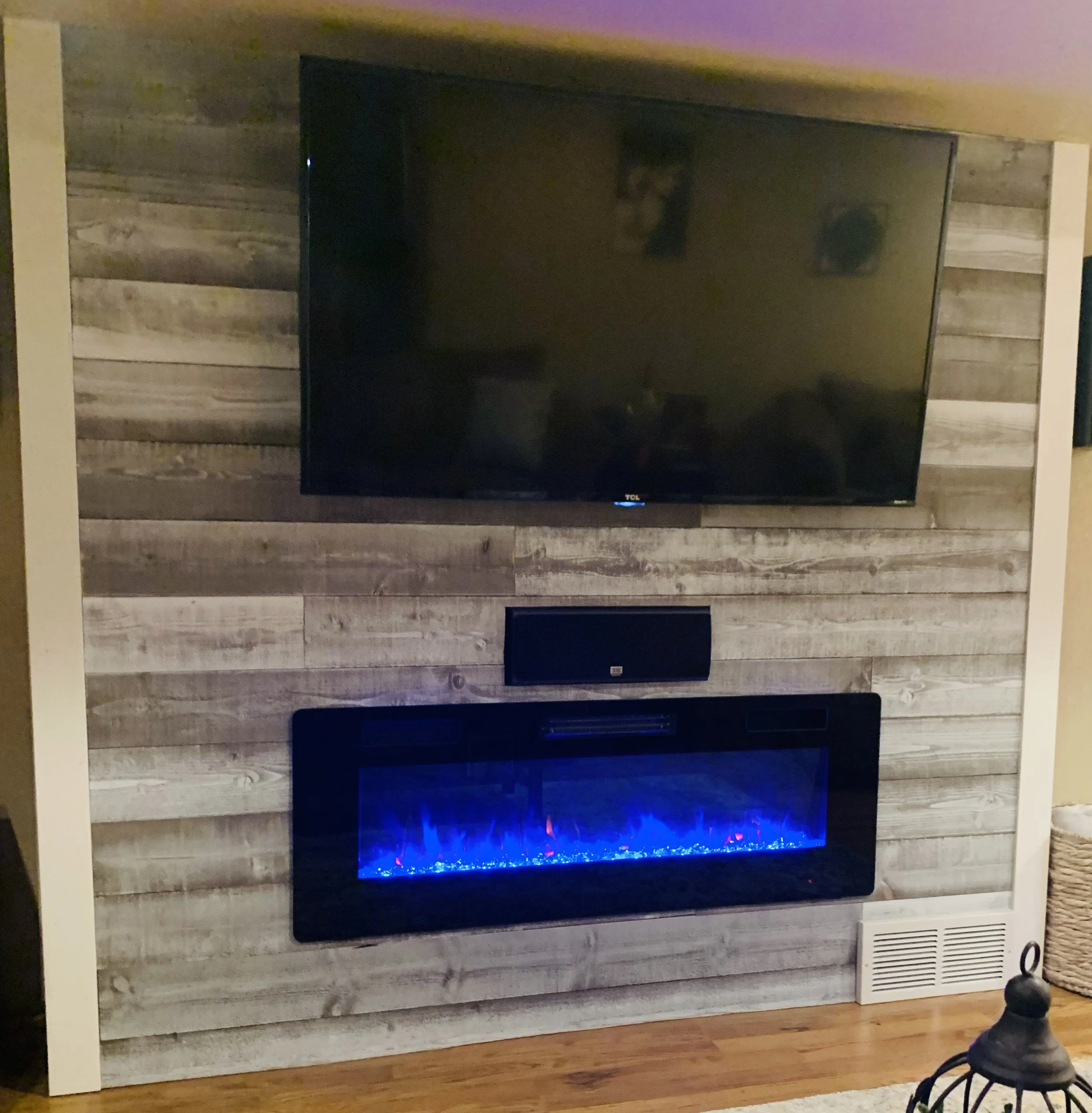 Wall-mounted TV and electric fireplace on wood panel wall