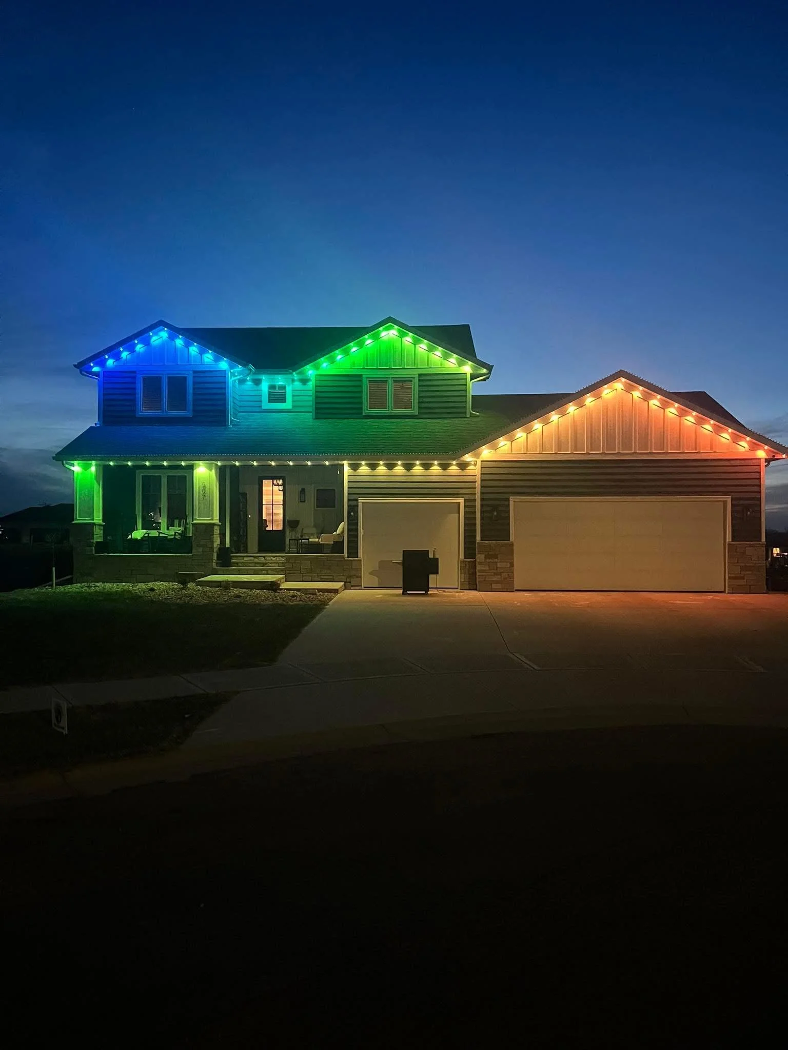 House with multicolored lights at night; blue, green, and red.