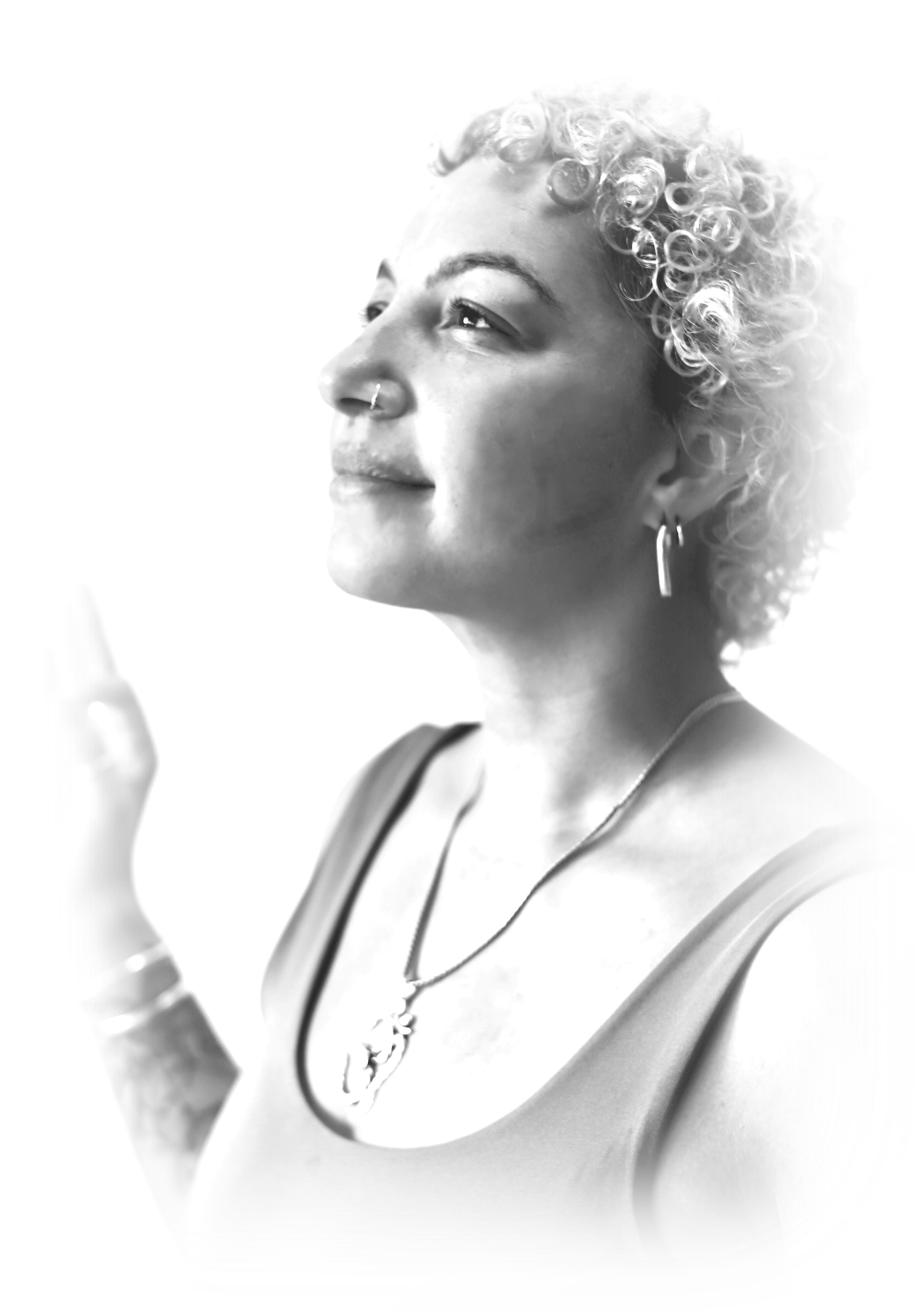 Black and white portrait of a woman with curly short hair, nose piercing, hoop earrings, wearing a sleeveless top, and a necklace, with a relaxed and confident expression.