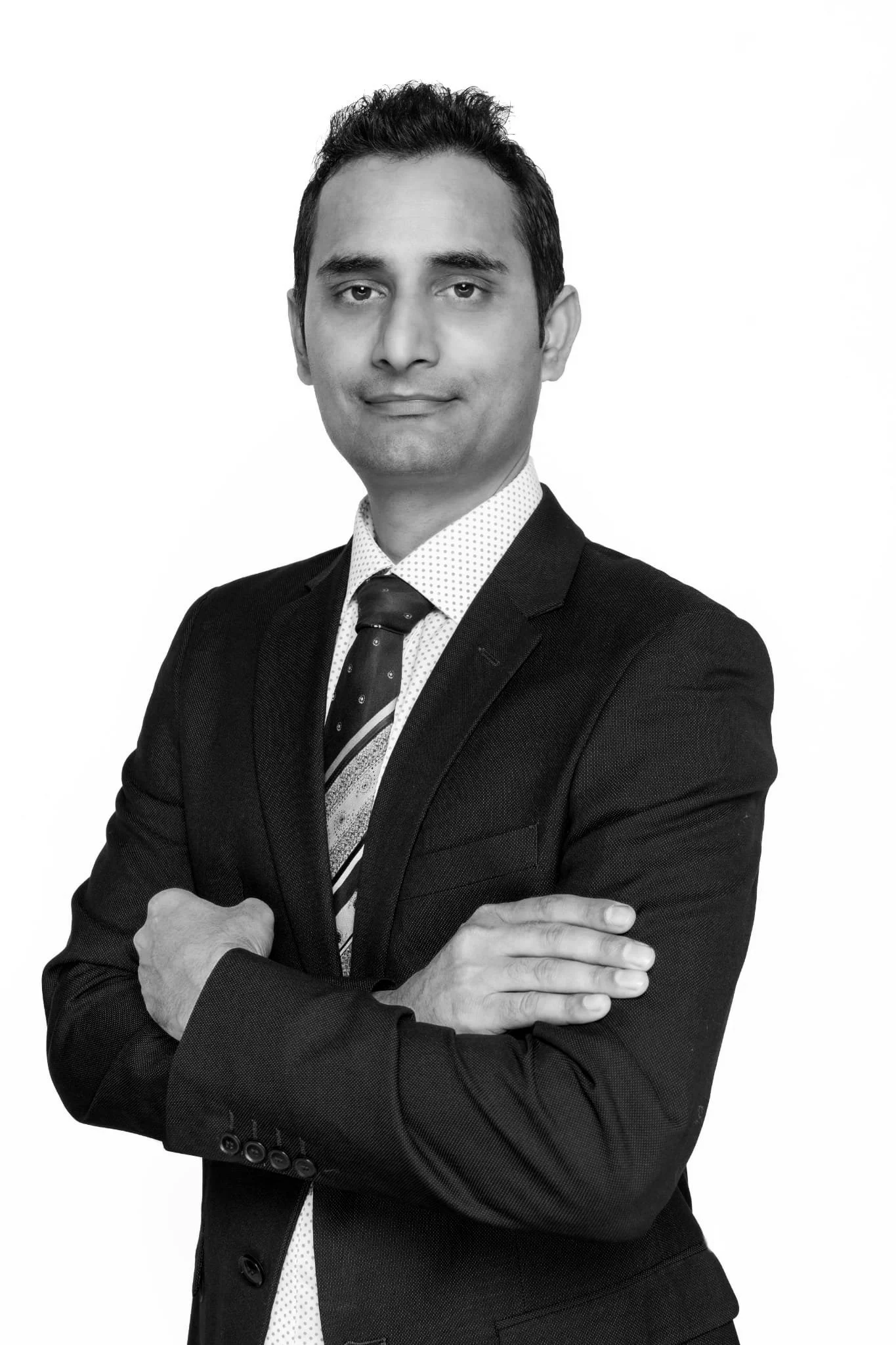 Black and white professional portrait of a man in a suit with arms crossed, looking at the camera.