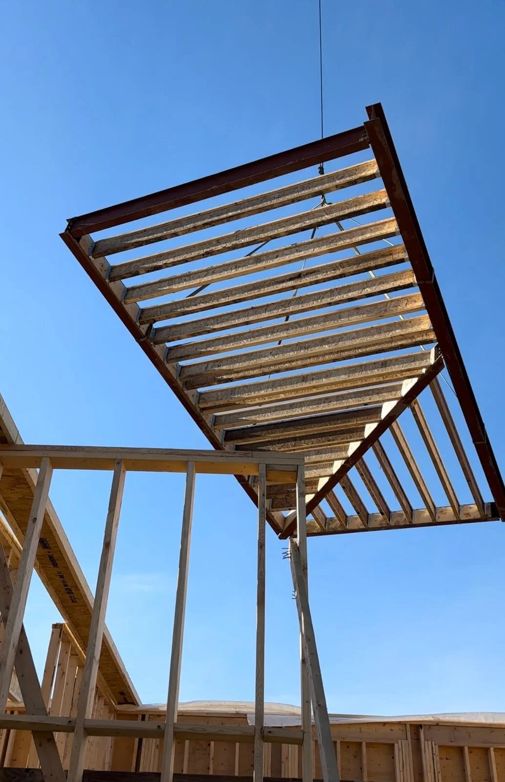 Construction site with wooden framing and an elevated wooden platform against a clear blue sky.