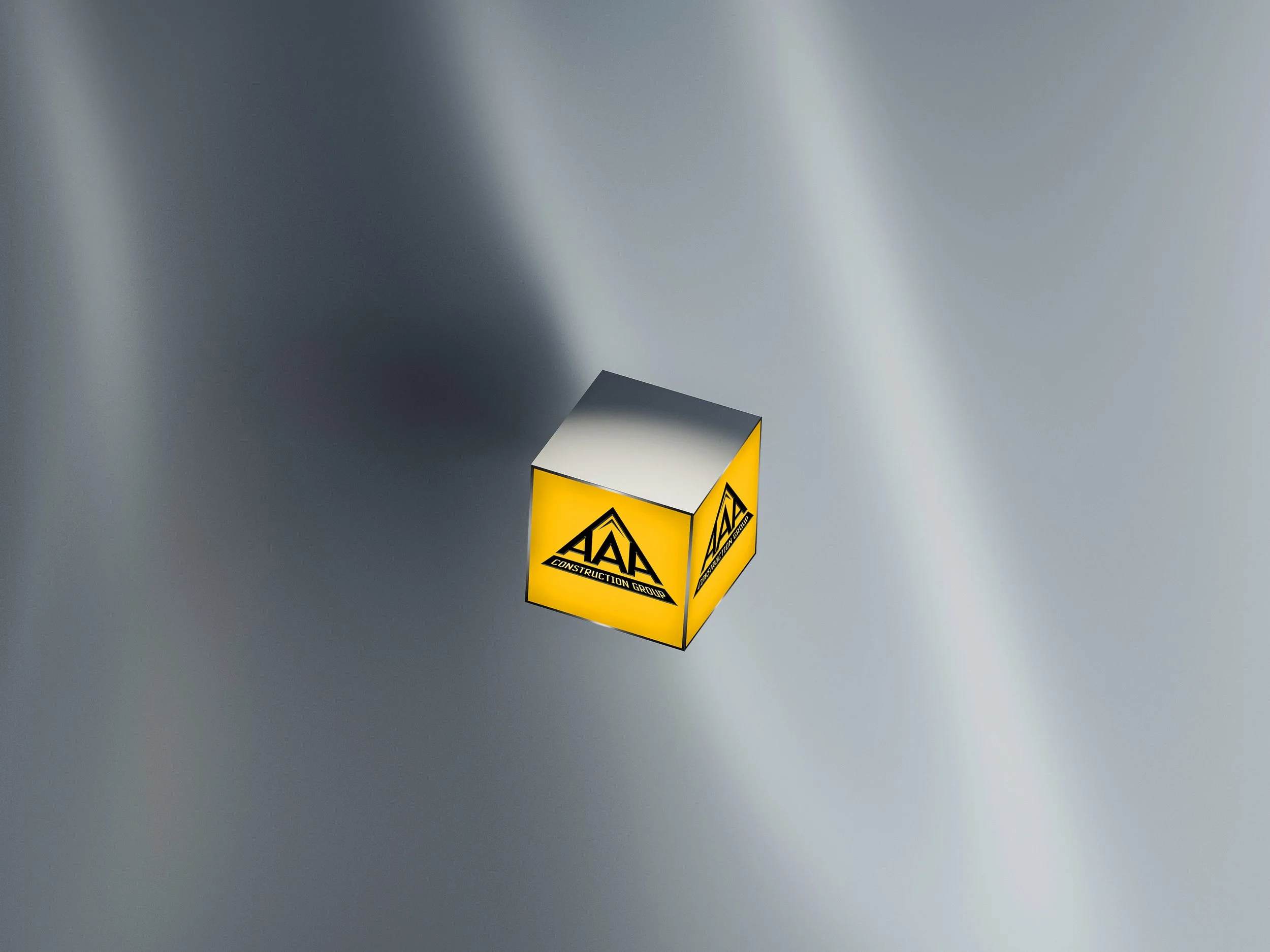 A small yellow cube with black and white logo on a reflective metallic surface.