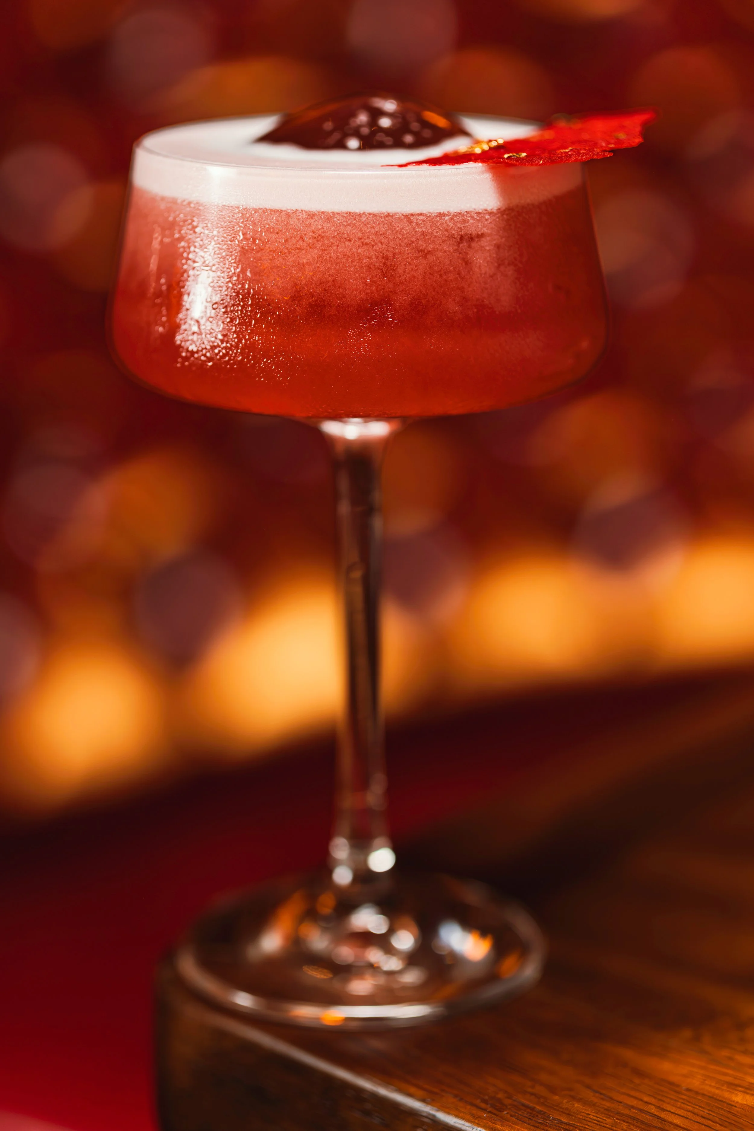 Cóctel en copa de cristal con hielo y una decoración de tocino y cereza