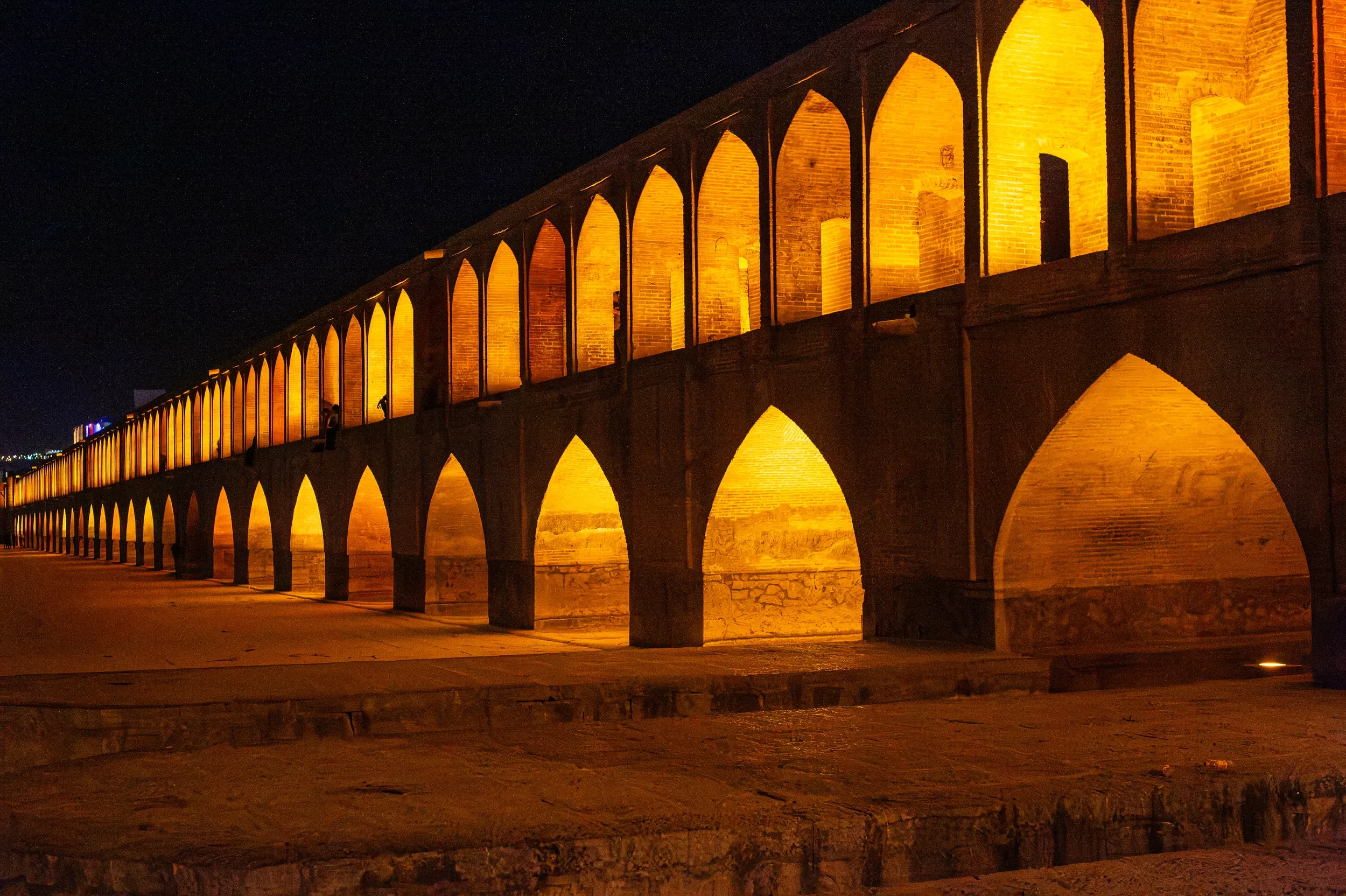 Si-o-se-pol Bridge in Isfahan, Iran, illuminated at night, with its historic arches glowing against the dark sky.