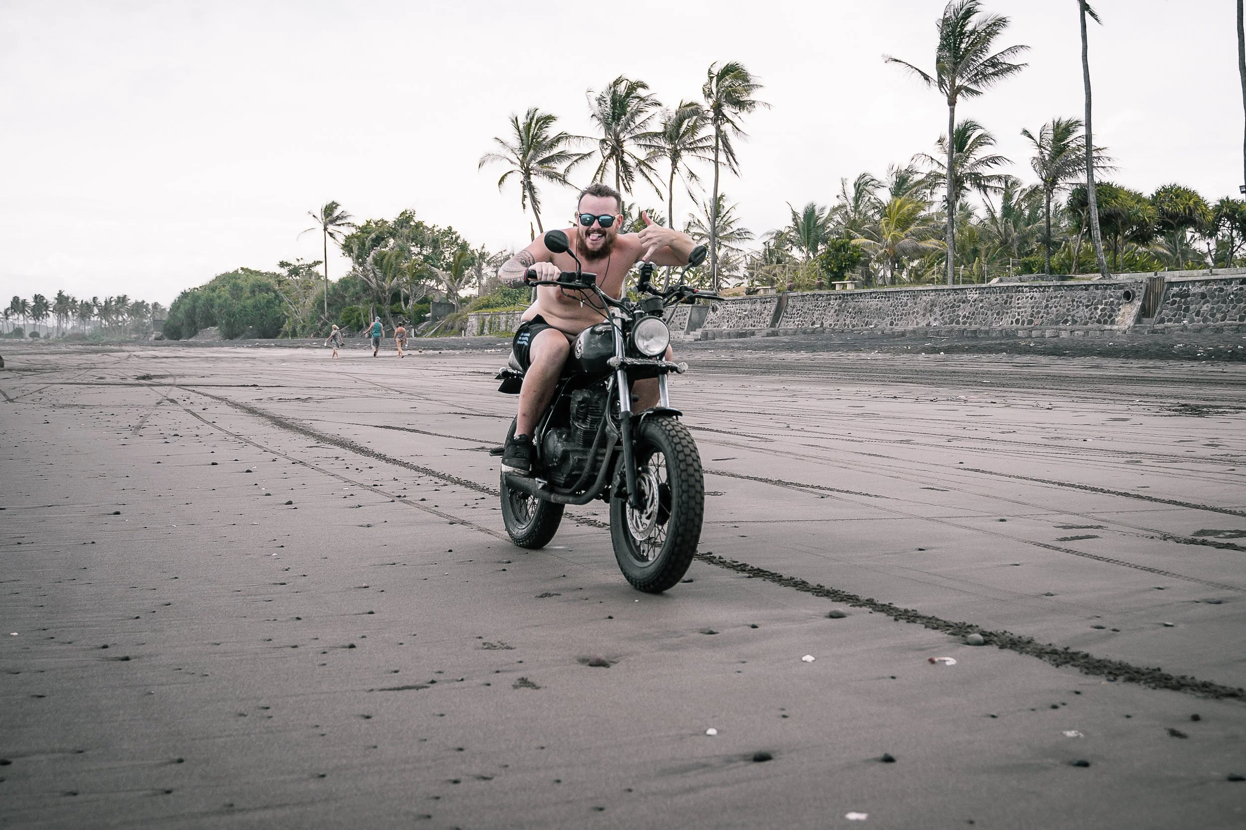 Man smiles for camera while riding his motorbike on the beach | Edmonton motorcycle photographer DarkShark Media