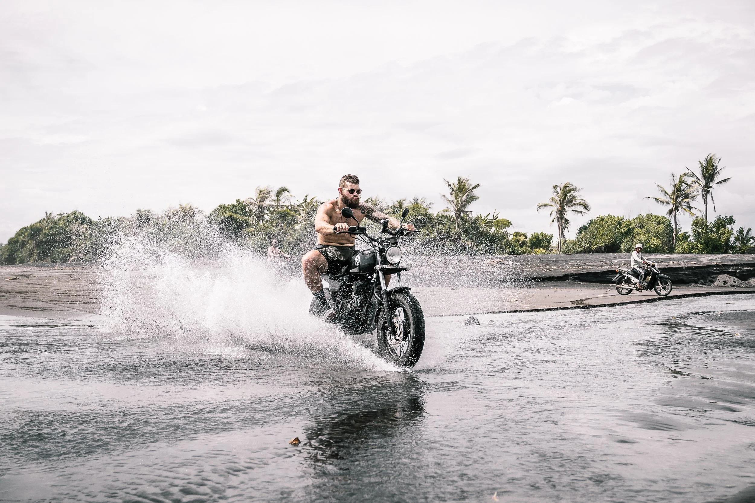 Man rides his motorcycle through the shallow water on beach | Edmonton motorcycle photographer DarkShark Media