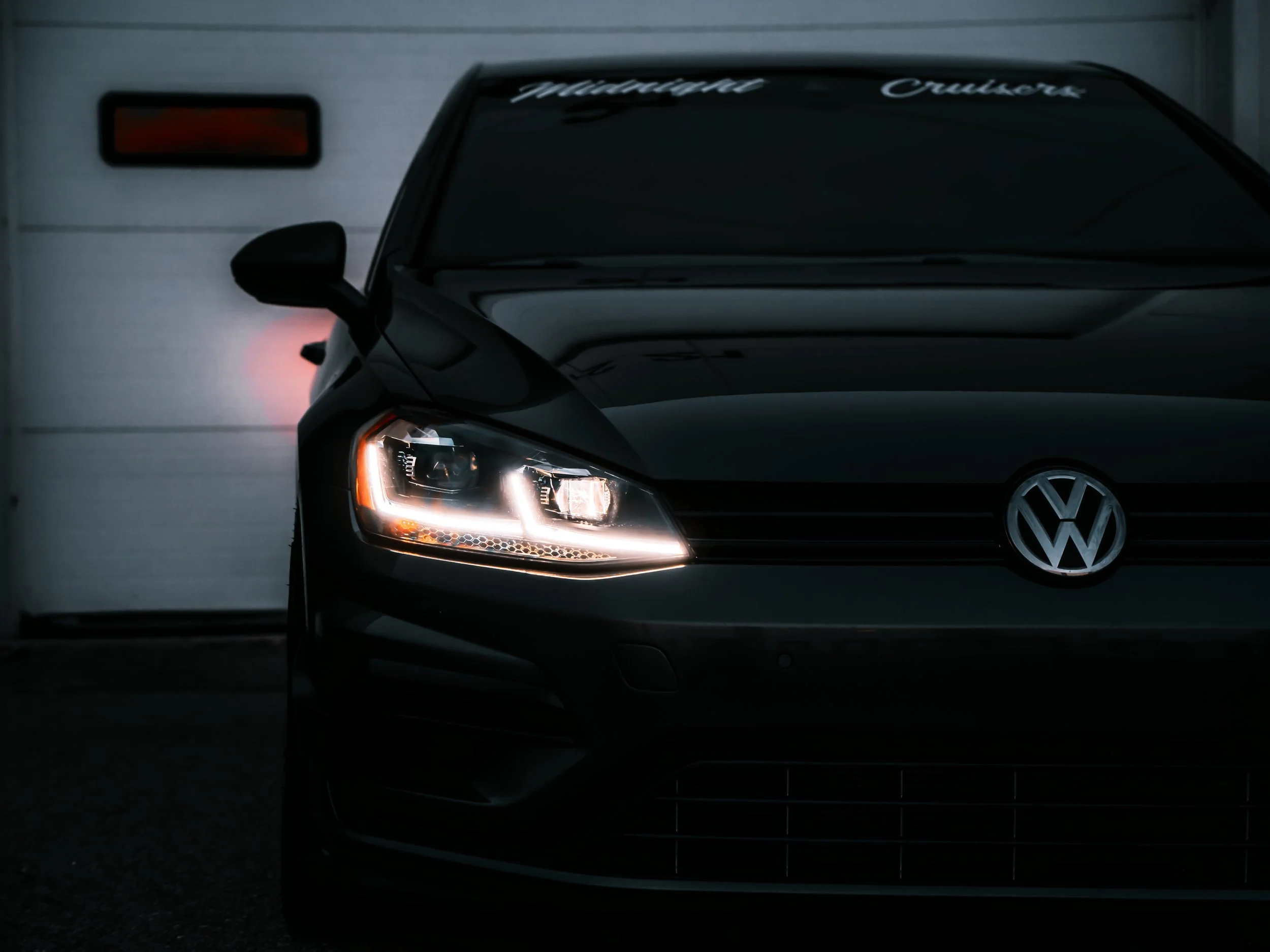 Volkswagen Golf parked in front of white door with lights on | Edmonton automotive photographer DarkShark Media