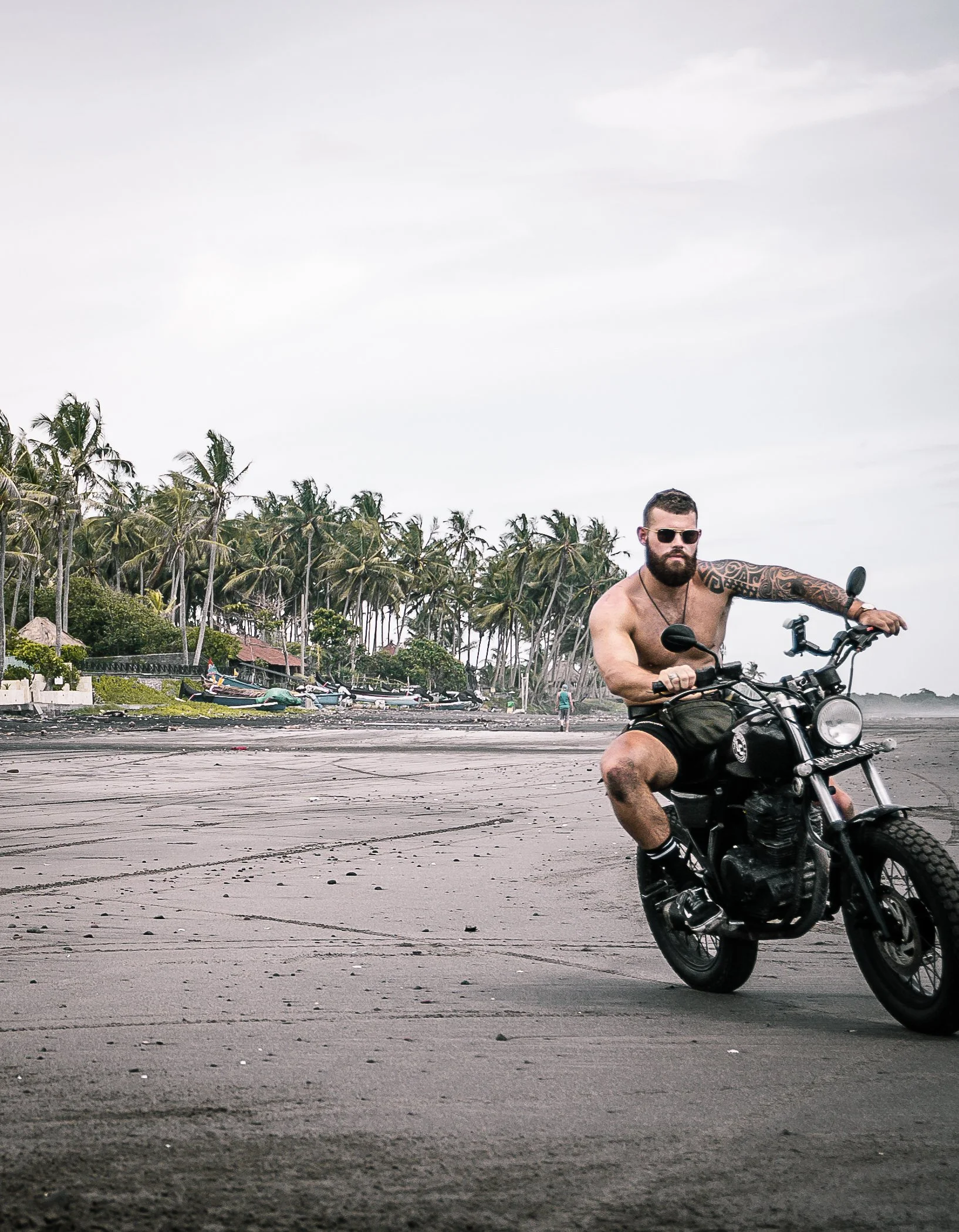 Tattooed man riding his motorcycle past camera on beach | Edmonton motorcycle photographer DarkShark Media