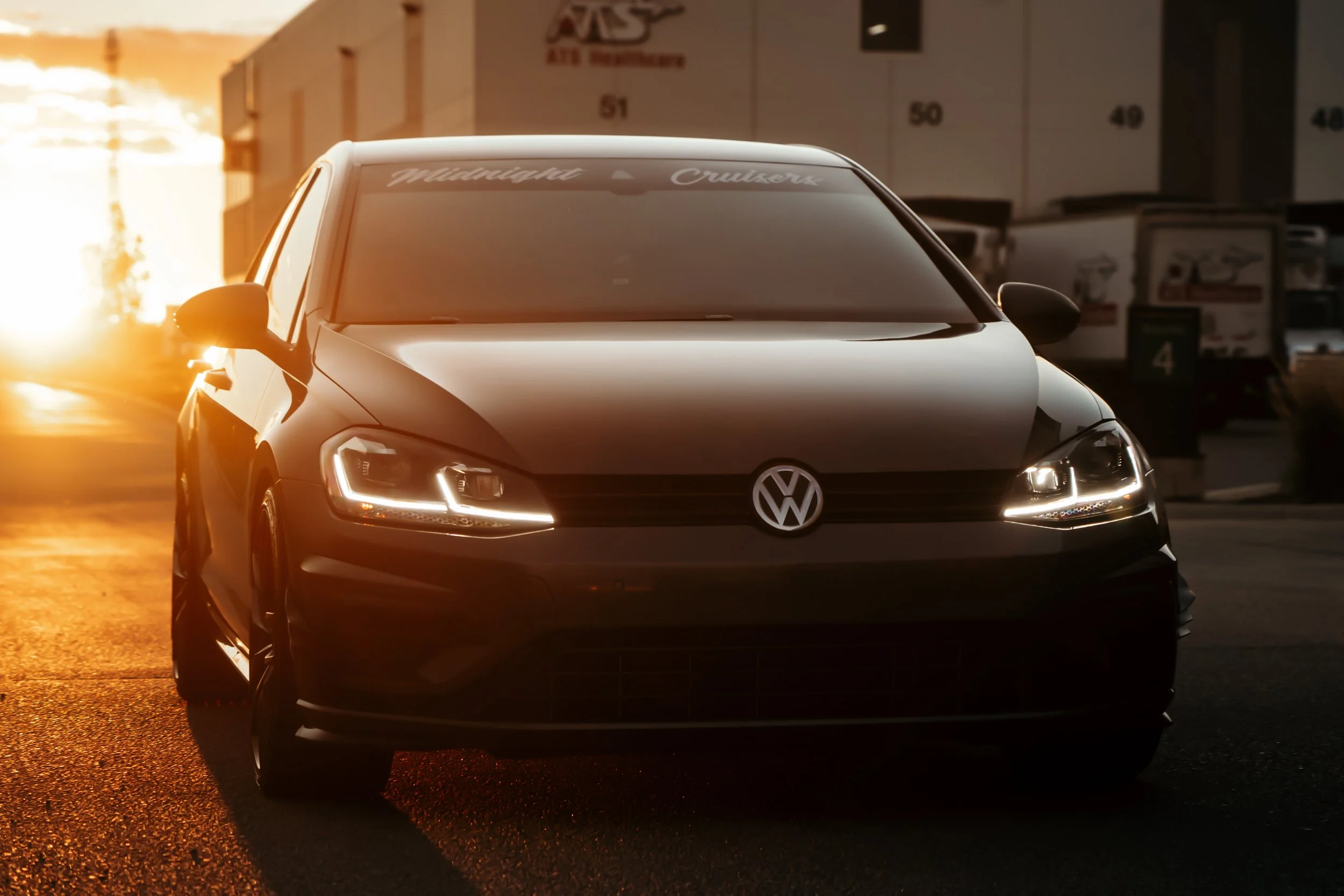 Volkswagen Golf parked in front of tractor trailers with sun setting in background in Edmonton | Edmonton automotive photographer DarkShark Media