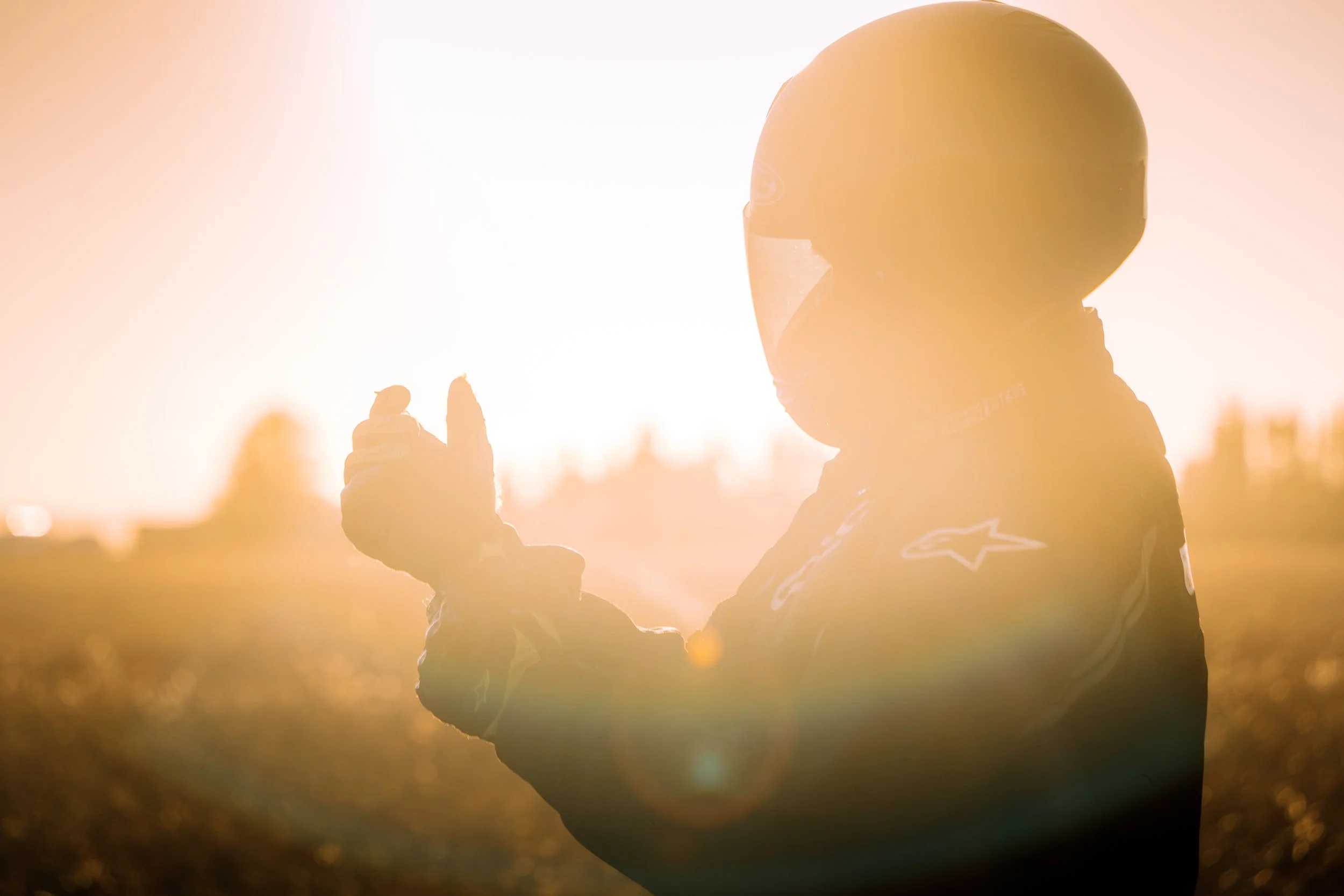 Backlit motorcycle rider puts on riding gloves | Edmonton motorcycle photographer DarkShark Media