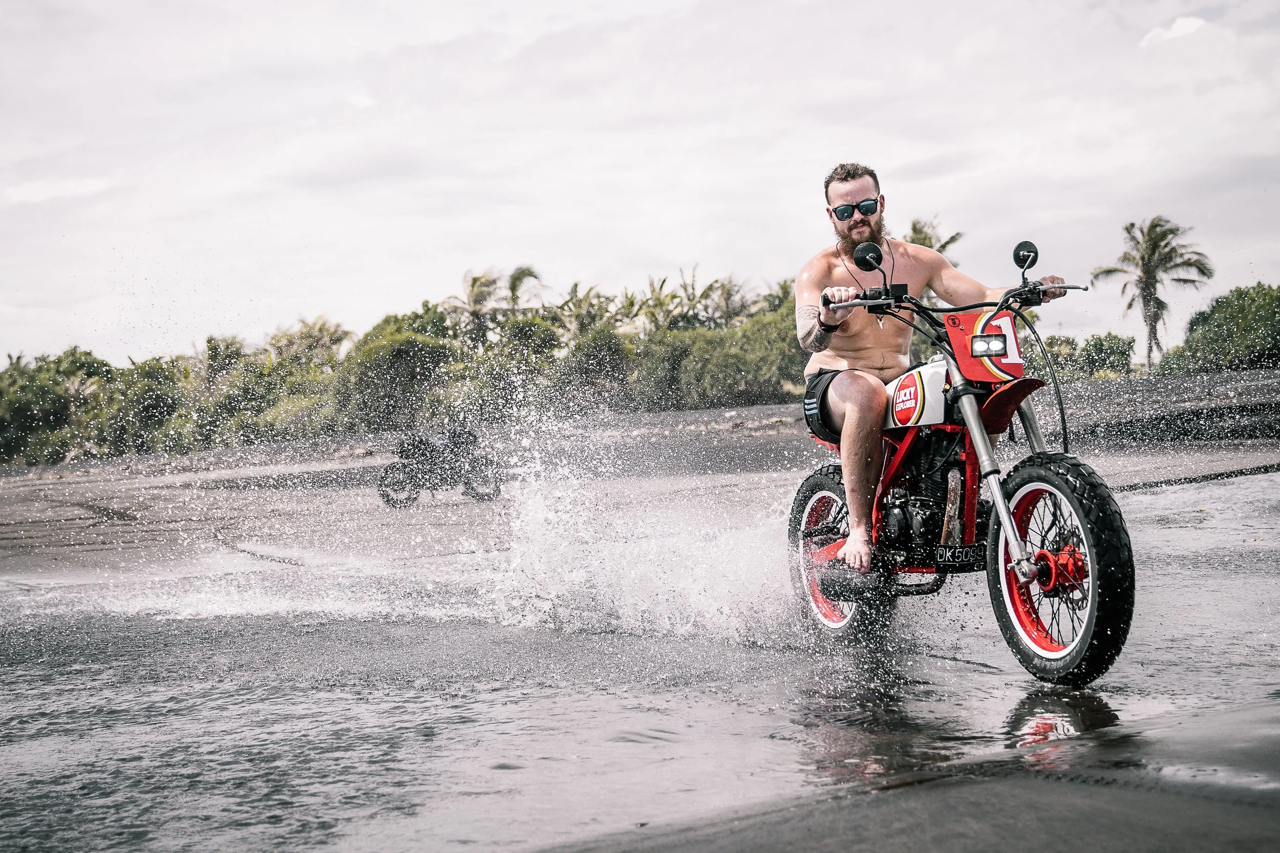 Two men ride motorbikes on the bach through water | Edmonton motorcycle photographer DarkShark Media