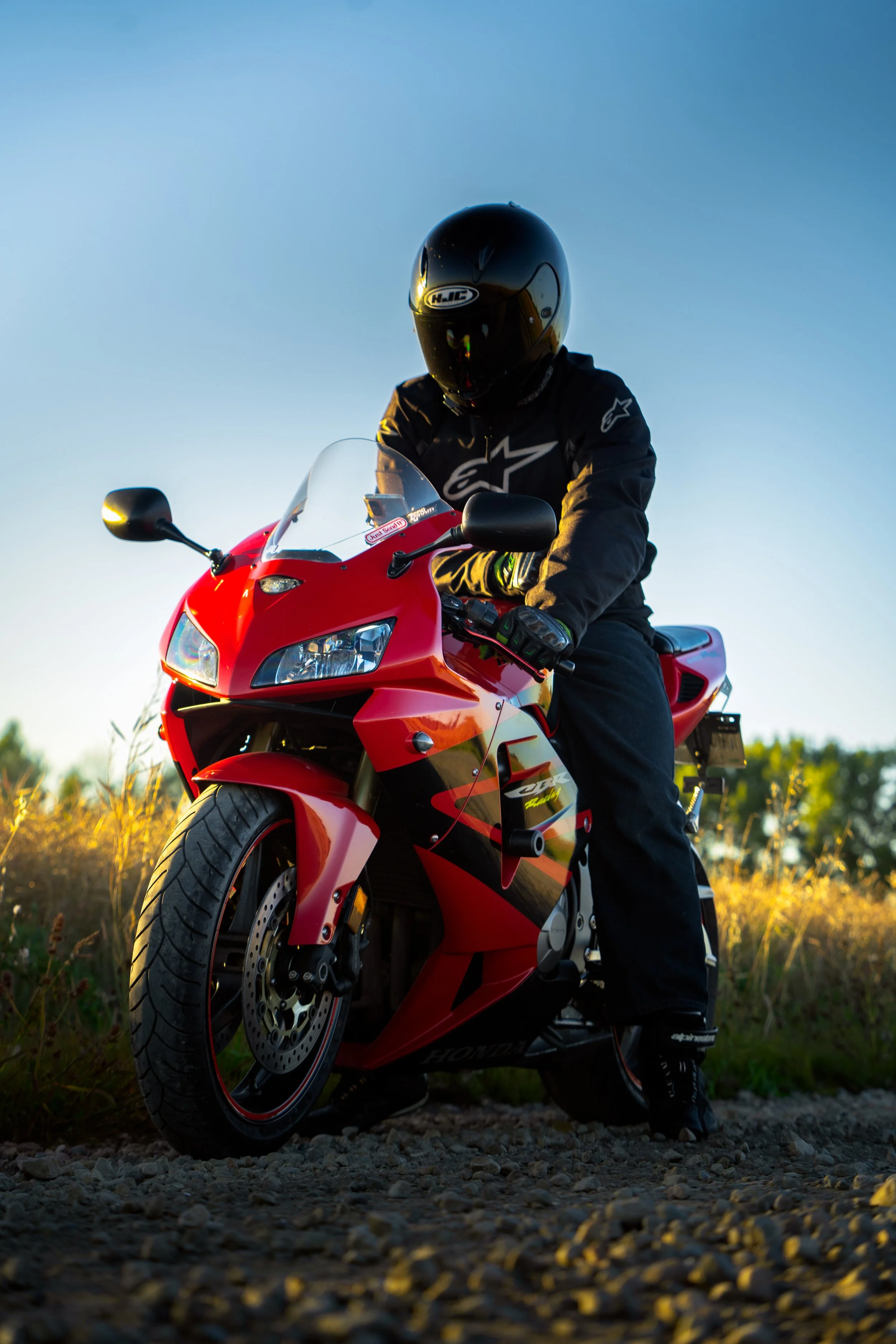 Rider sits on motorcycle on blue sky day in front of field | Edmonton motorcycle photographer DarkShark Media