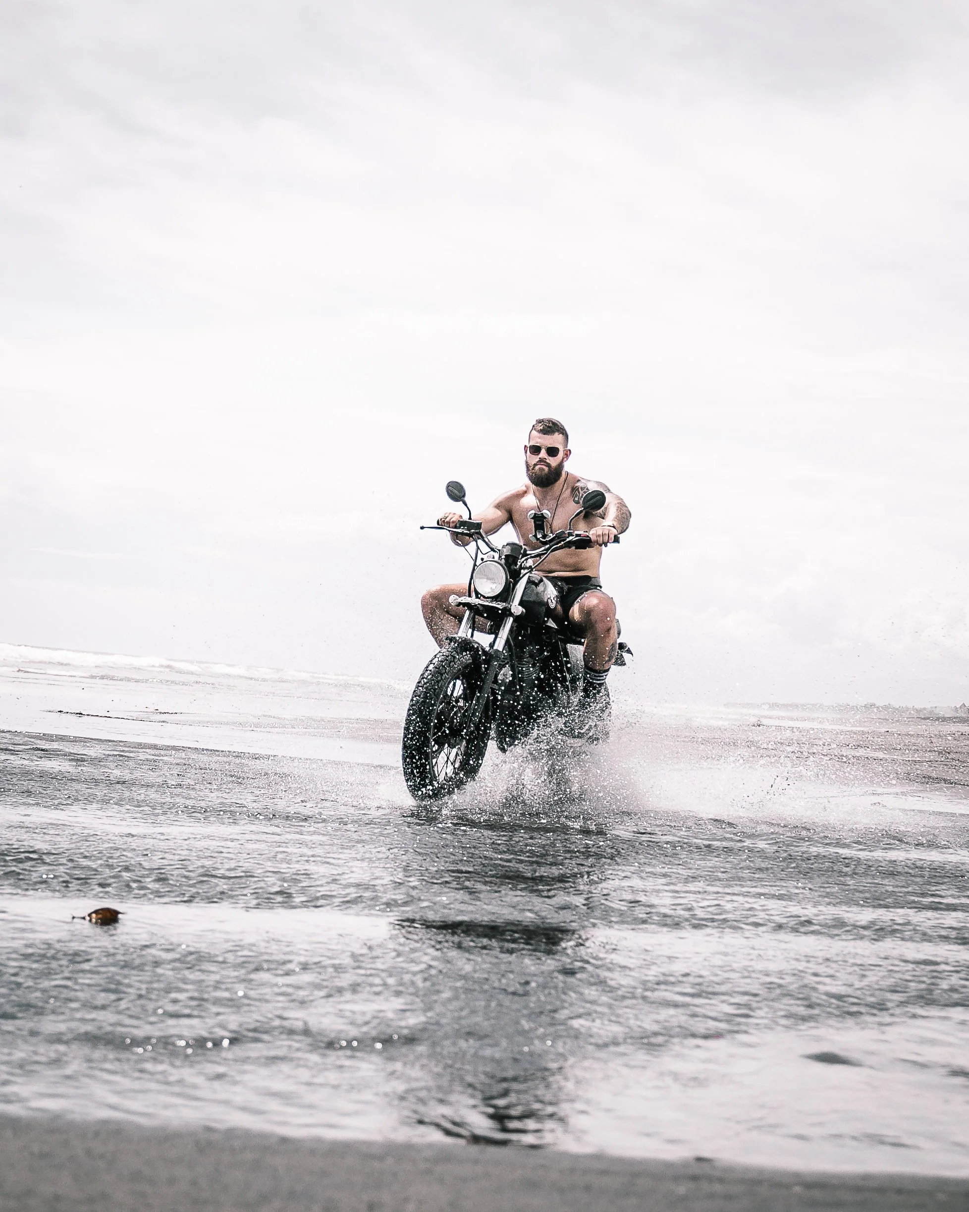Shirtless man on black motorcycle rides motorbike through the water | Edmonton motorcycle photographer DarkShark Media