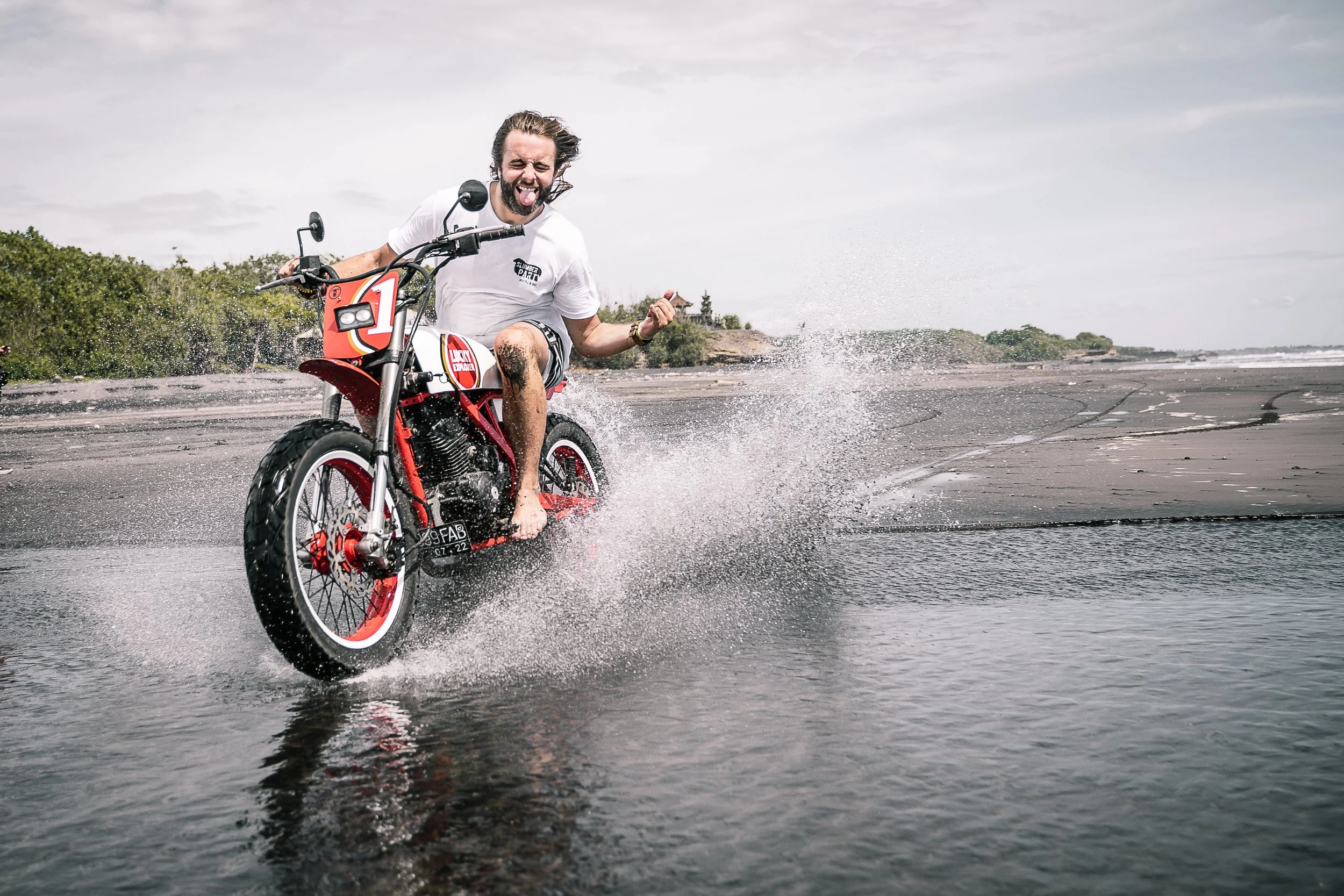 Long-haired man rides motorbike through the water along the beach | Edmonton motorcycle photographer DarkShark Media