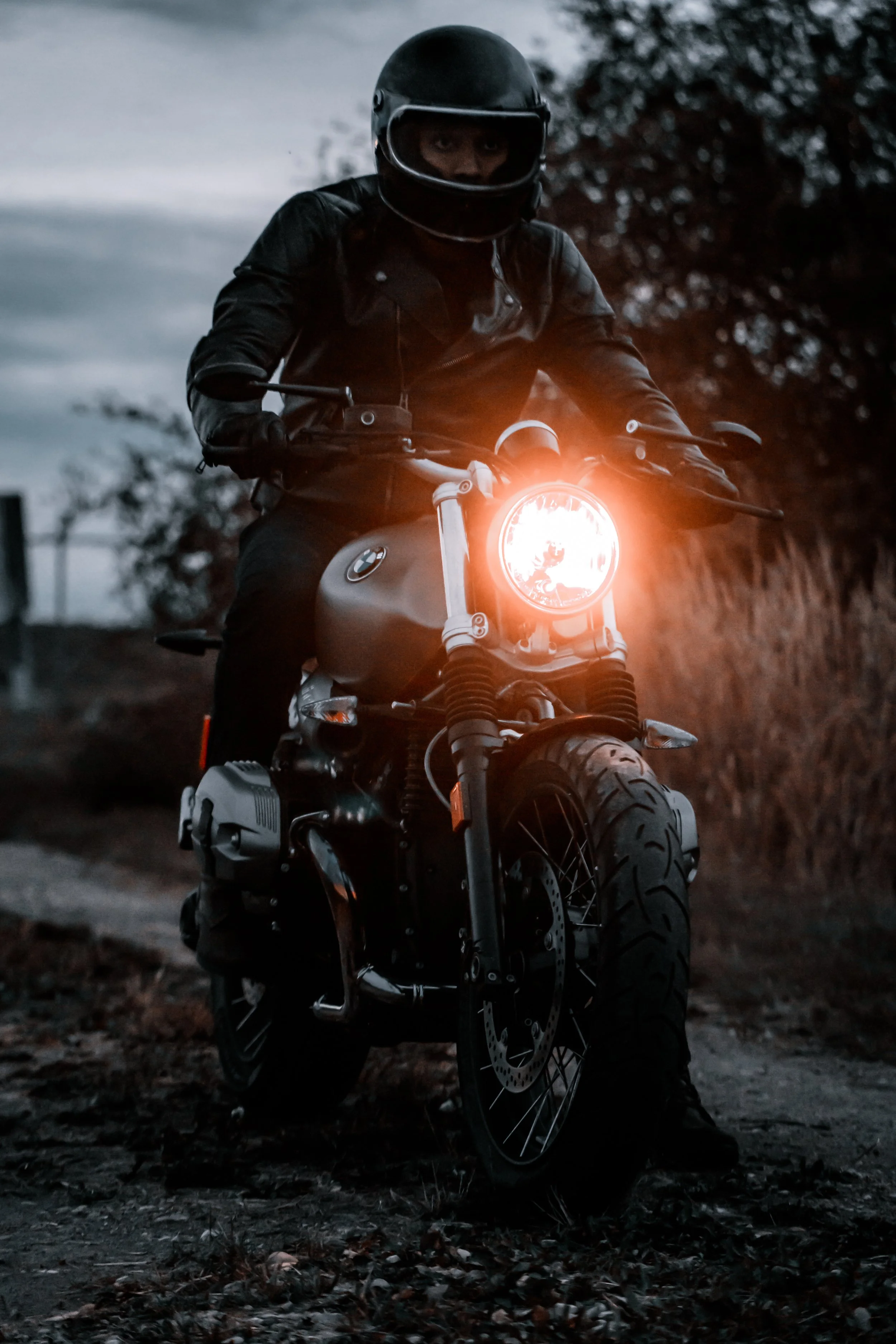 A man rides his BMW R Nine T motorcycle with headlight on | Edmonton motorcycle photographer DarkShark Media