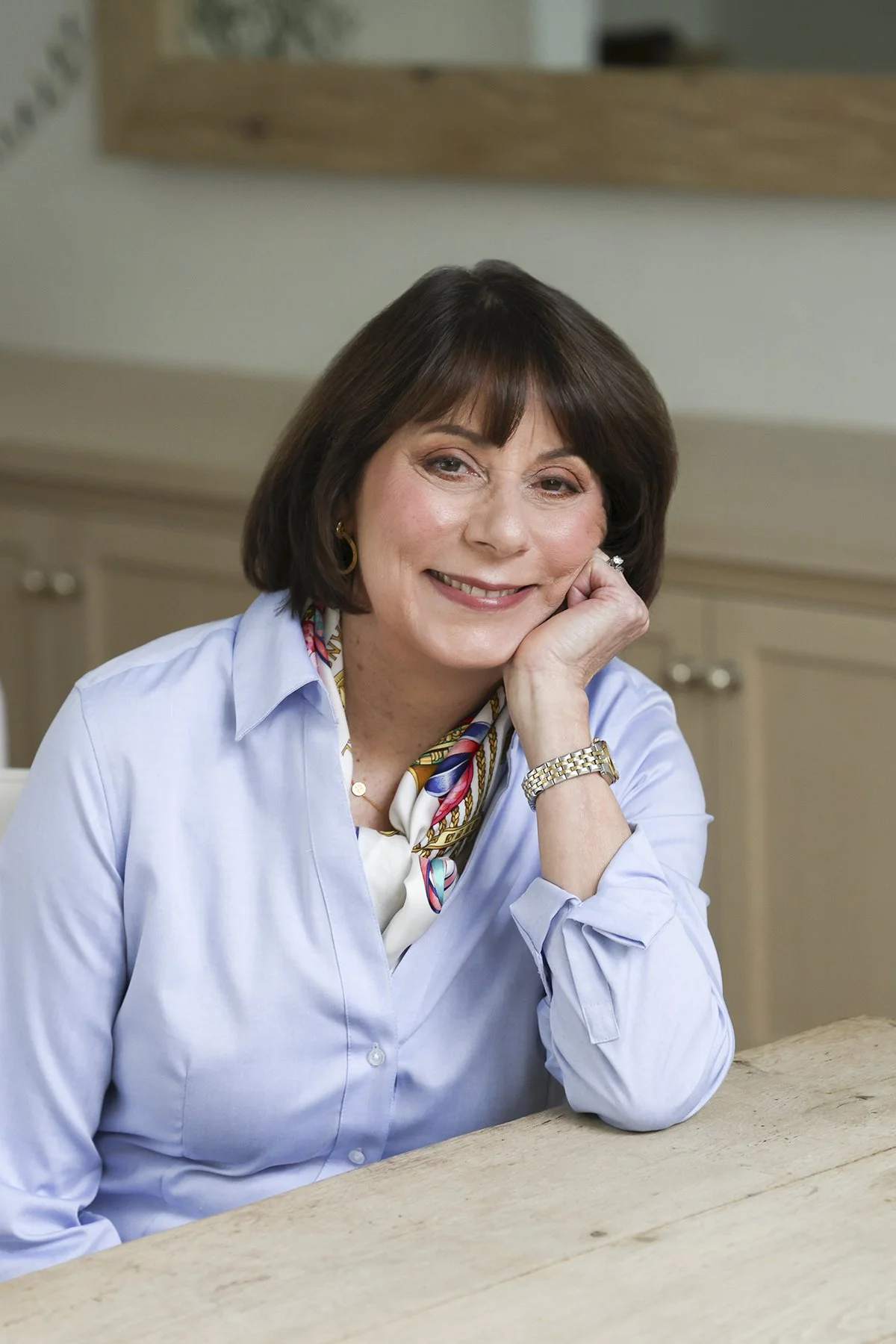 Mary Gilles, part of Gilles Randall Group, a top realtor in Menlo Park, Atherton, Portola Valley, and Woodside, smiling with her head resting on her hand.