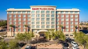 Front view of Drury Plaza Hotel with a large sign on top, surrounded by trees and parking lot.