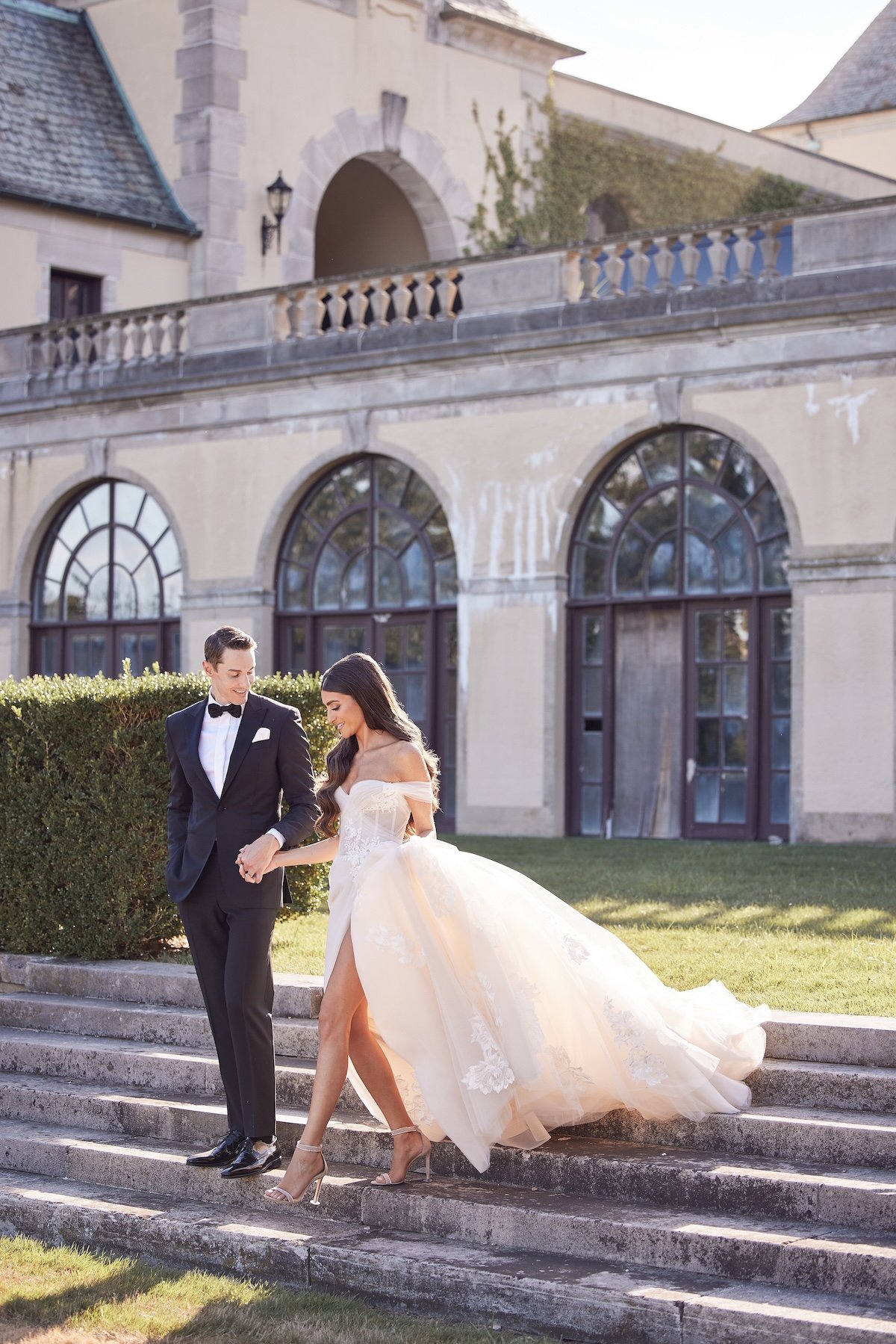 Bride and groom walking down the steps of a historic estate in New York during their destination wedding, captured by Lost in Love Photography.
