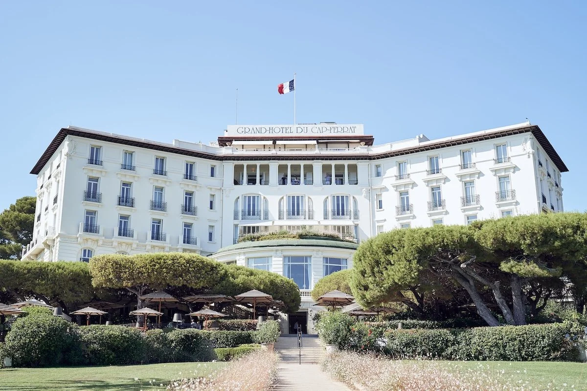 Iconic French Riviera hotel exterior with grand white architecture and manicured grounds.