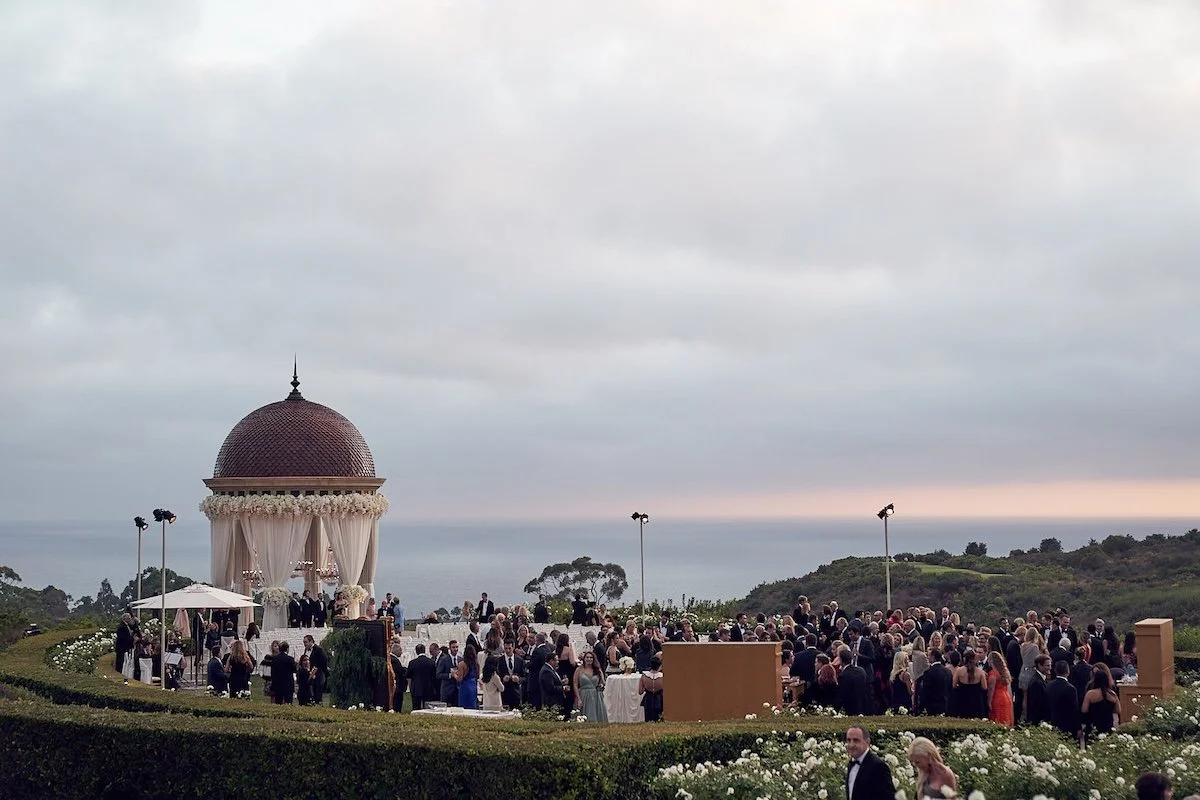 Outdoor wedding ceremony in California wine country with guests gathered at sunset, captured by Lost in Love Photography.