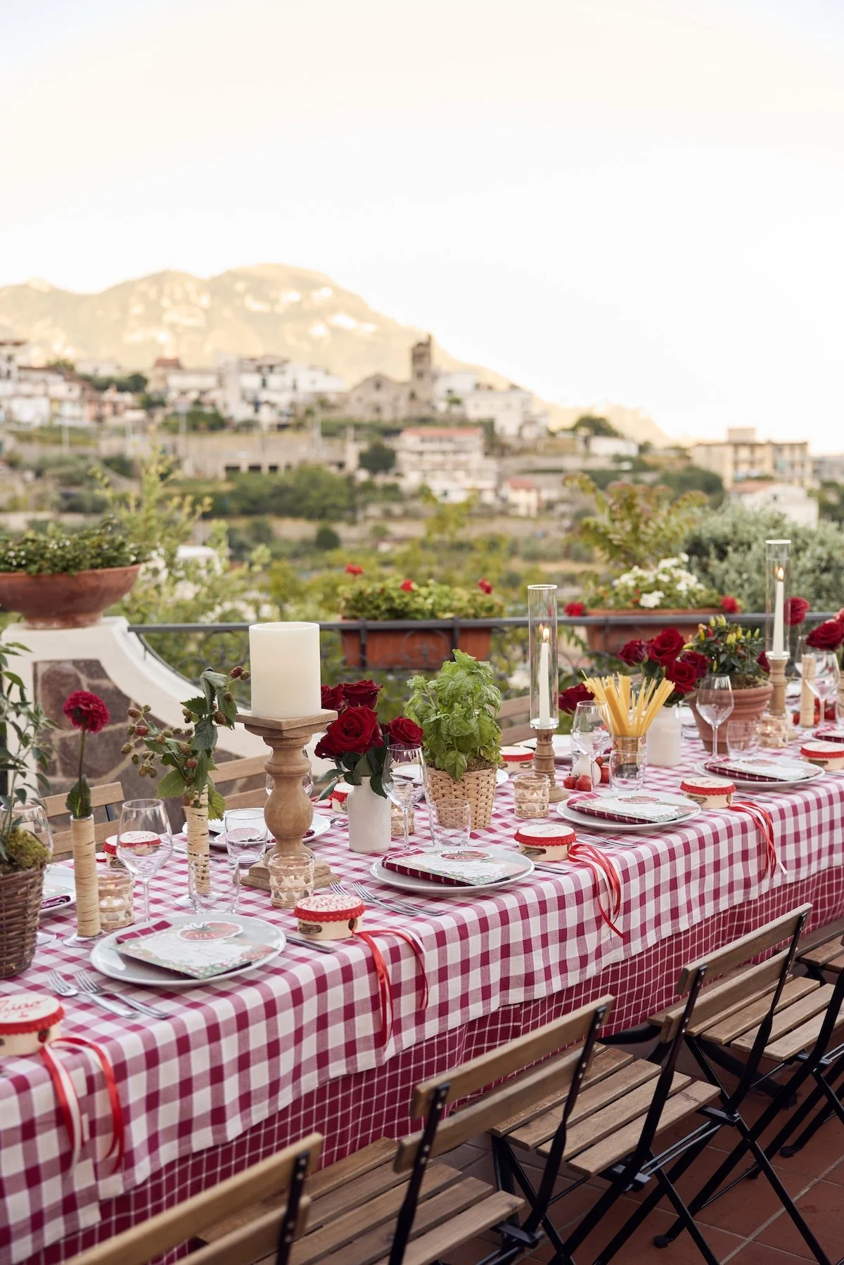Al fresco wedding reception table with red gingham linens, colorful florals, and coastal views on the Amalfi Coast.