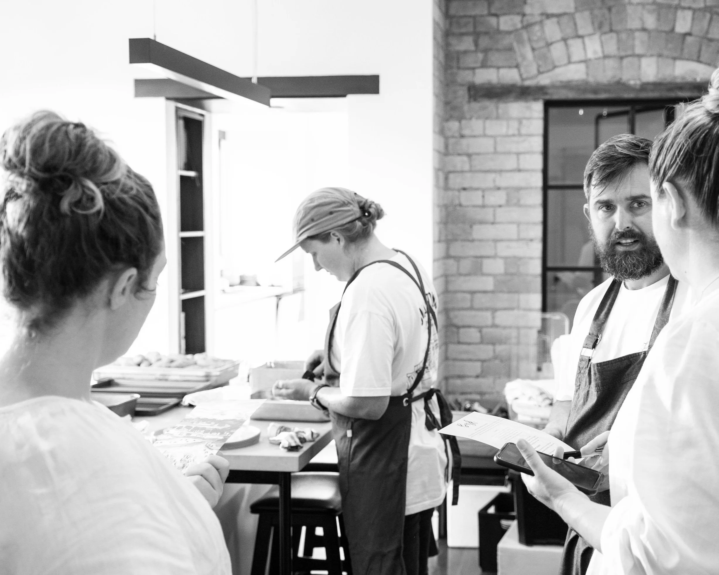 The Season & Savour team preparing food in a kitchen, while others work at a counter.