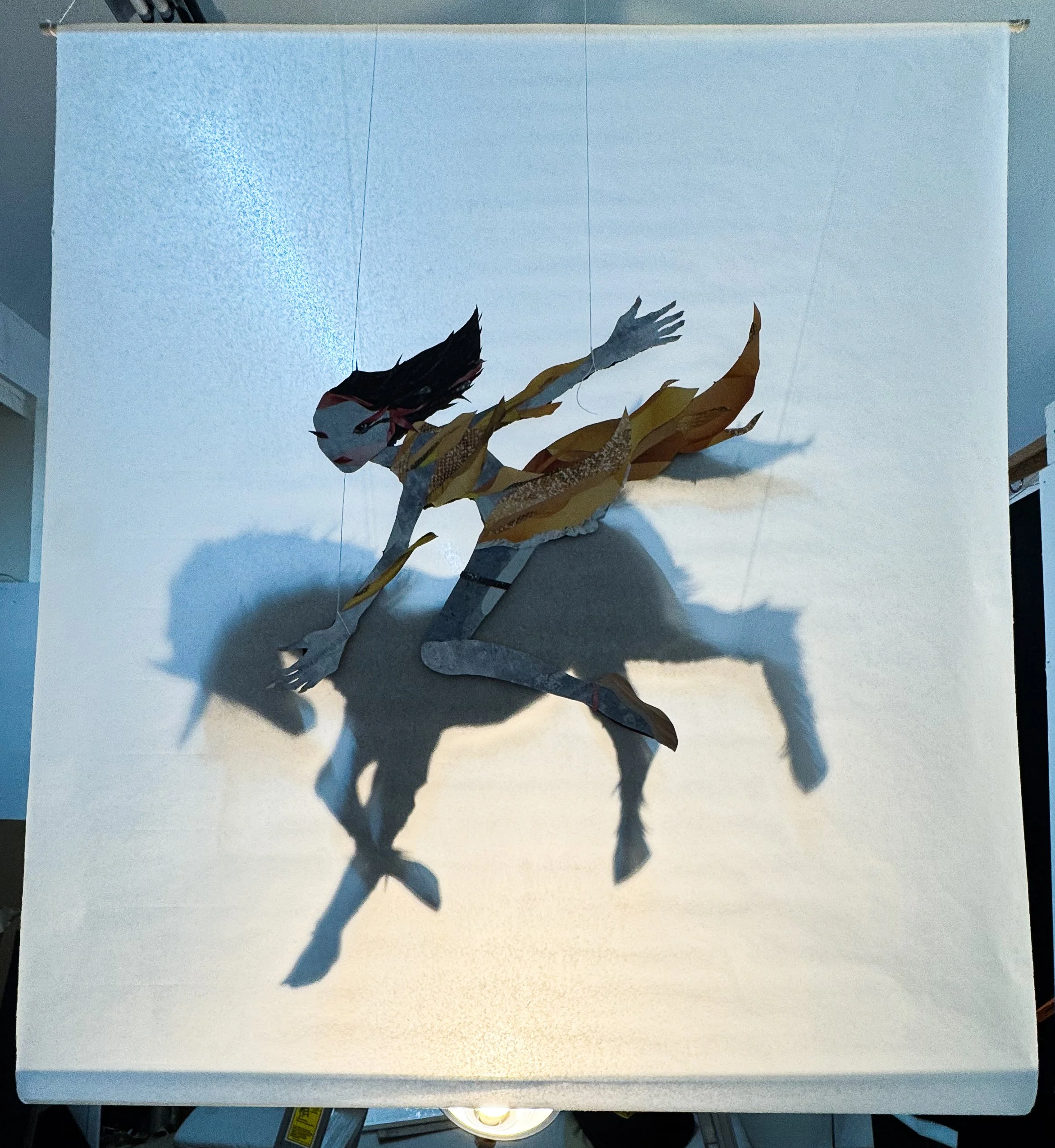 Christina Welzer
Ghost Rider, 2026
Cut paper, string, mulberry paper, wooden dowel, and light
45 x 39 in