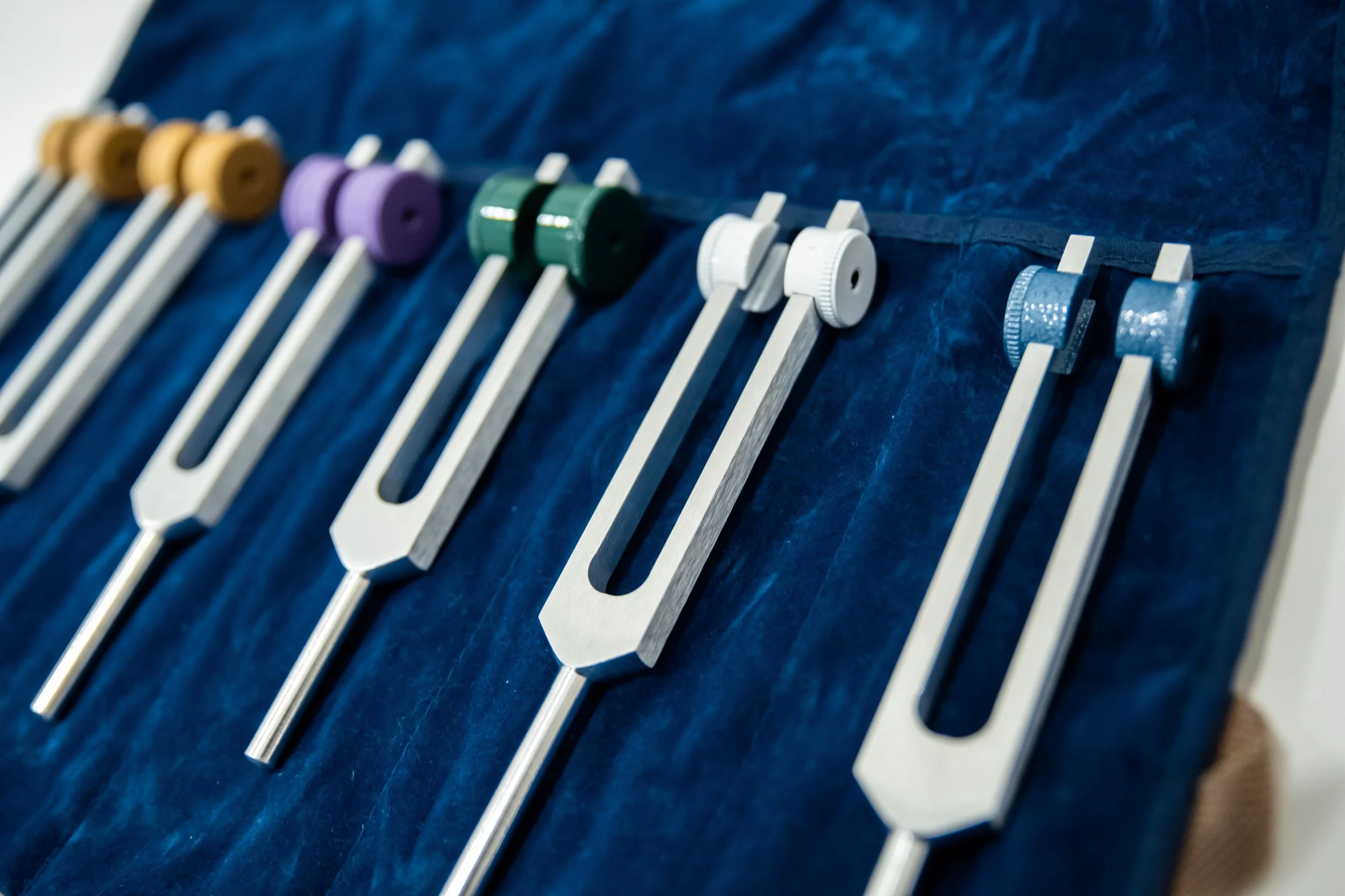 Set of colorful guitar tuning pegs arranged in a row on a blue surface.