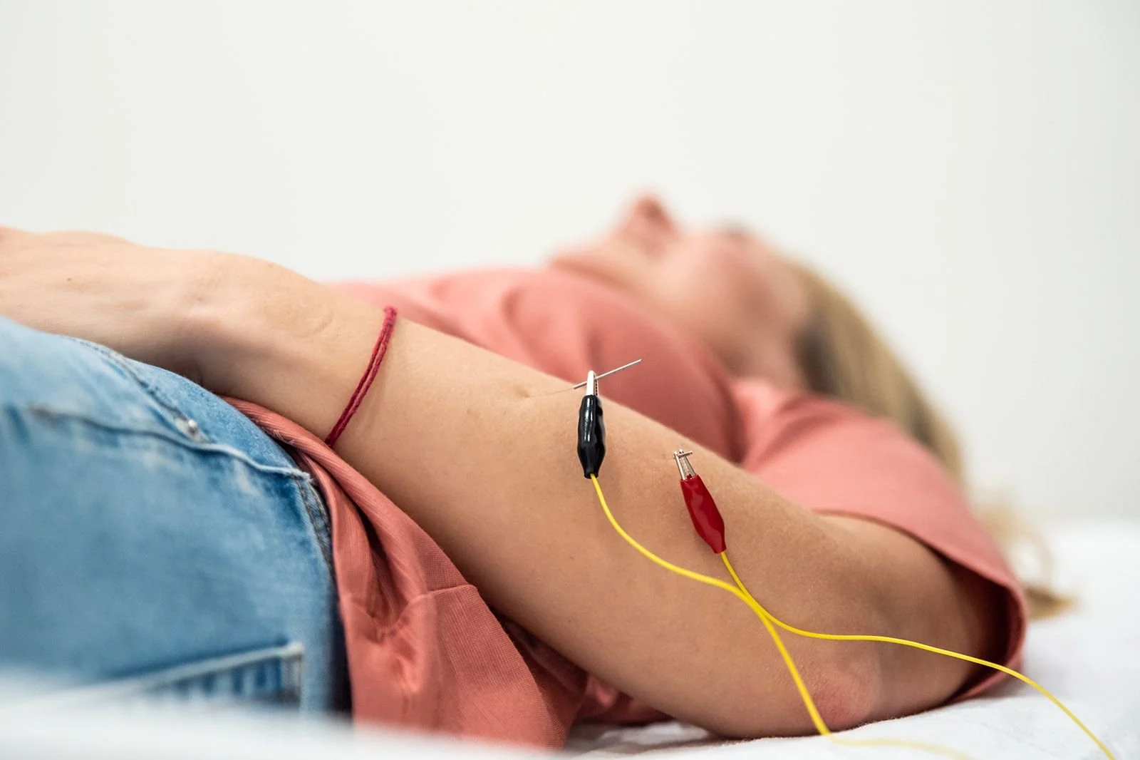 A woman lying on a bed, receiving a blood donation with a needle inserted into her arm, connected to tubes.