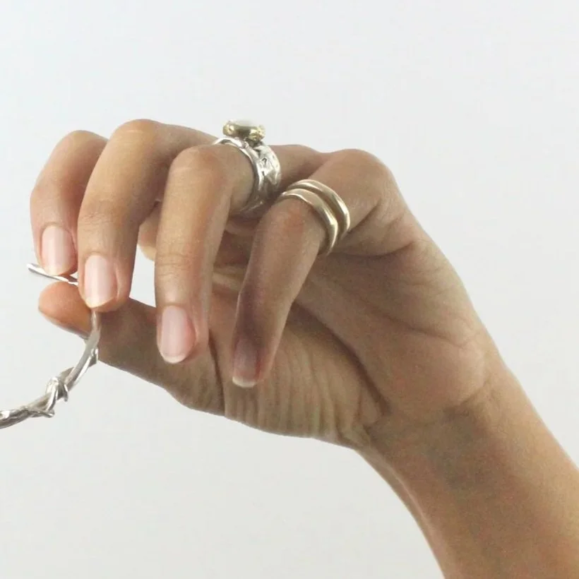model hand wearing stacked gold rings with organic texture and imperfect shape