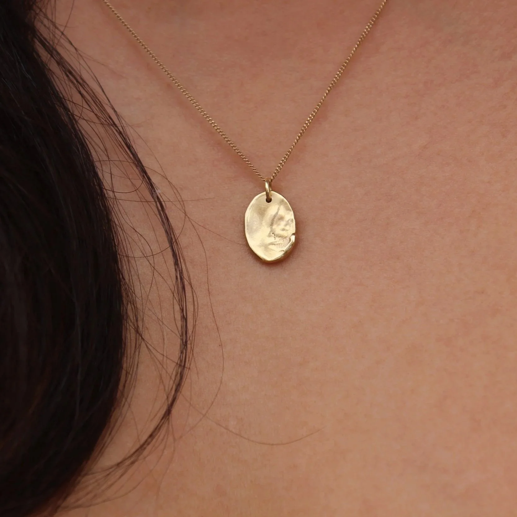 model wearing a gold necklace with water-like texture