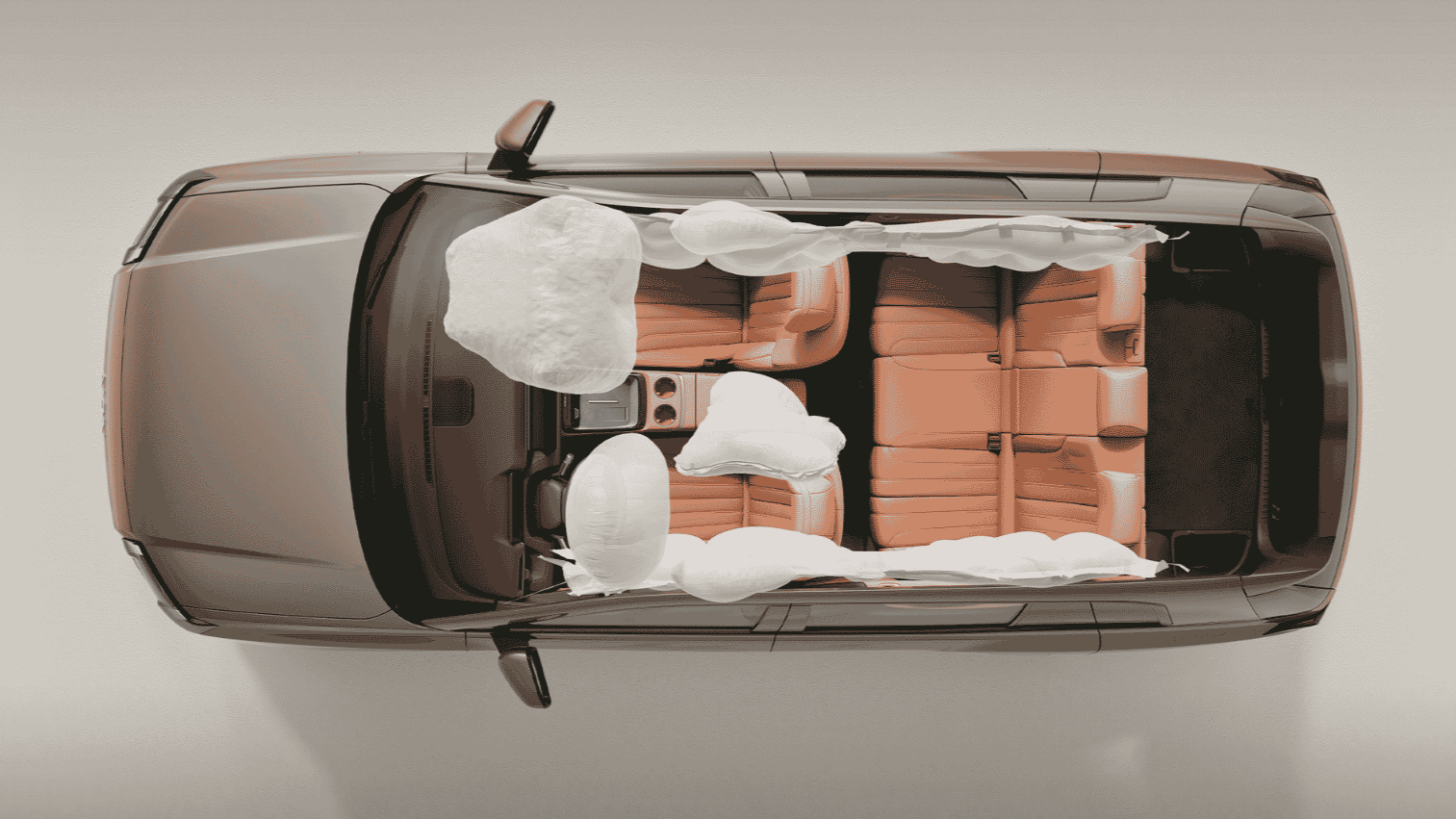 Top-down view of a car interior with deployed airbags and tan seats.