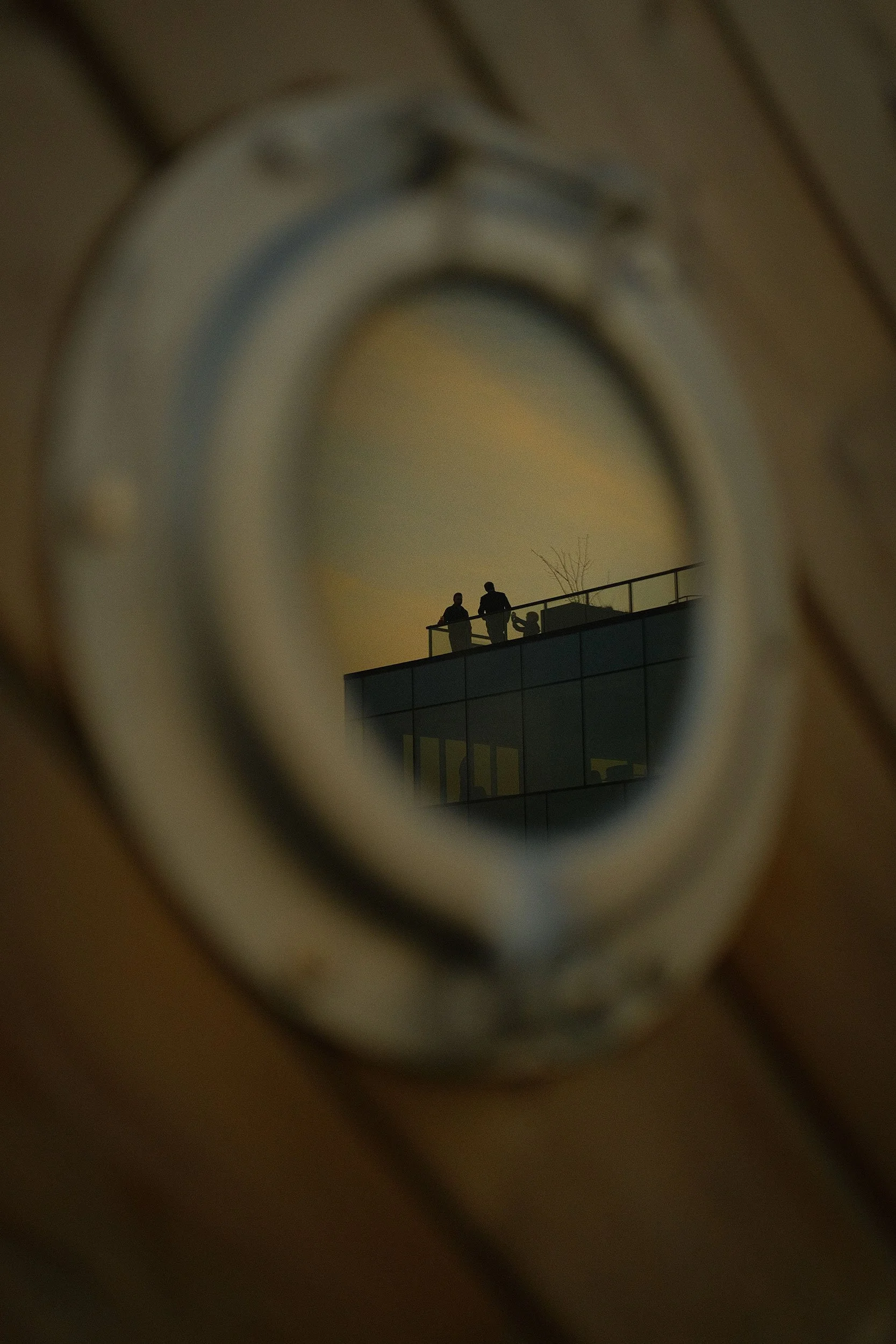 People on a rooftop patio at reflected in a small window.