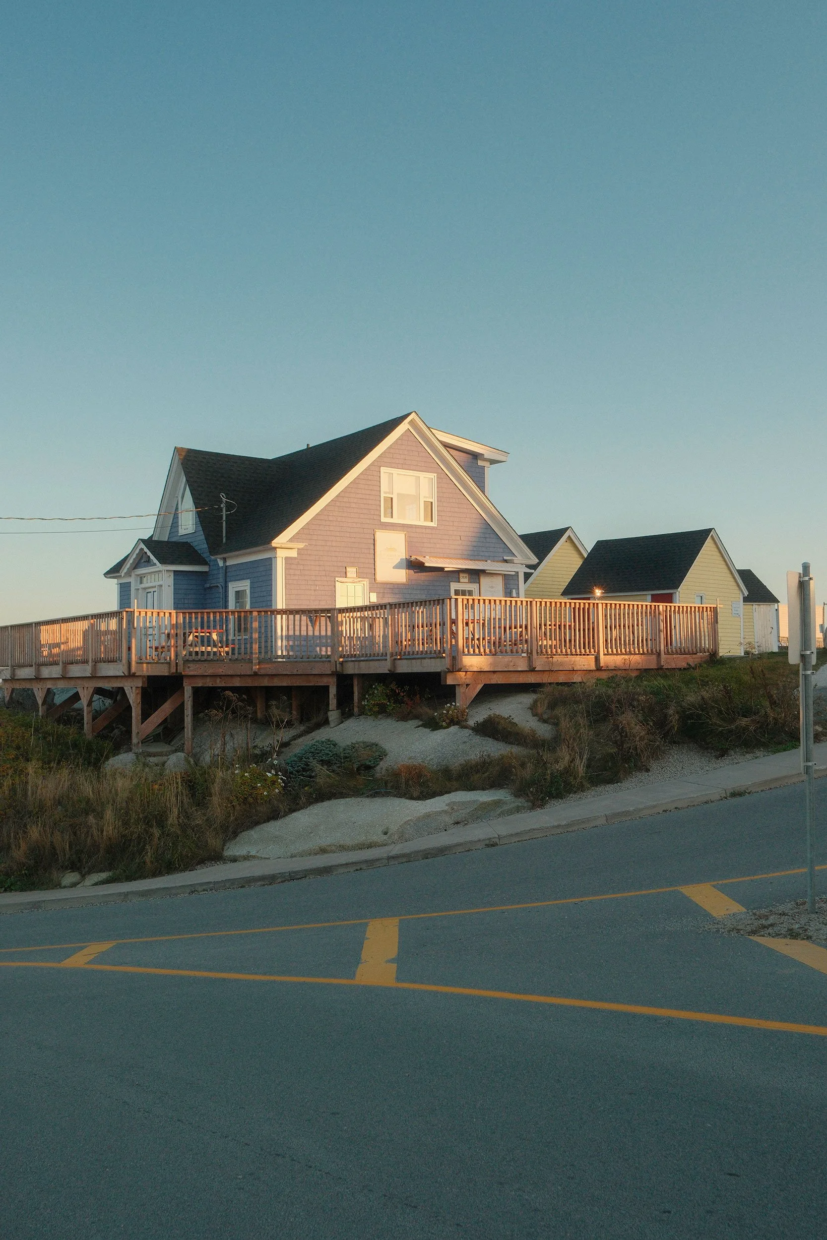 Coastal structures with raised wooden decks beside a road at sunset. Peggy's Cove.