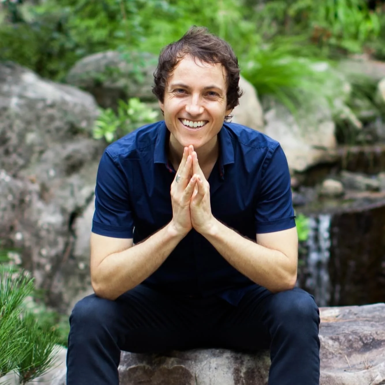 Simon Spire sitting in a rock garden and smiling at the camera.