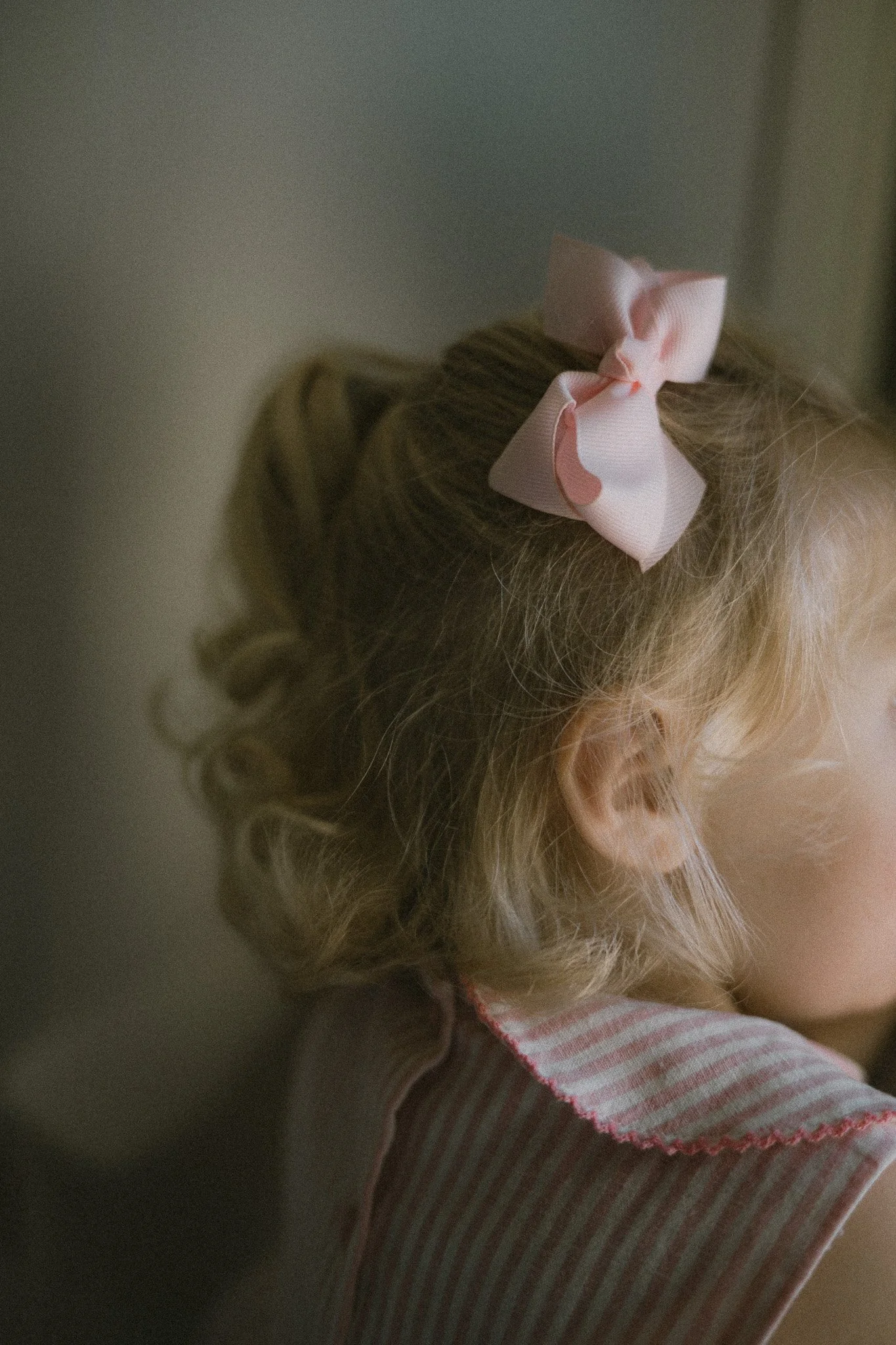 Barn med krusigt hår och rosa rosett i håret