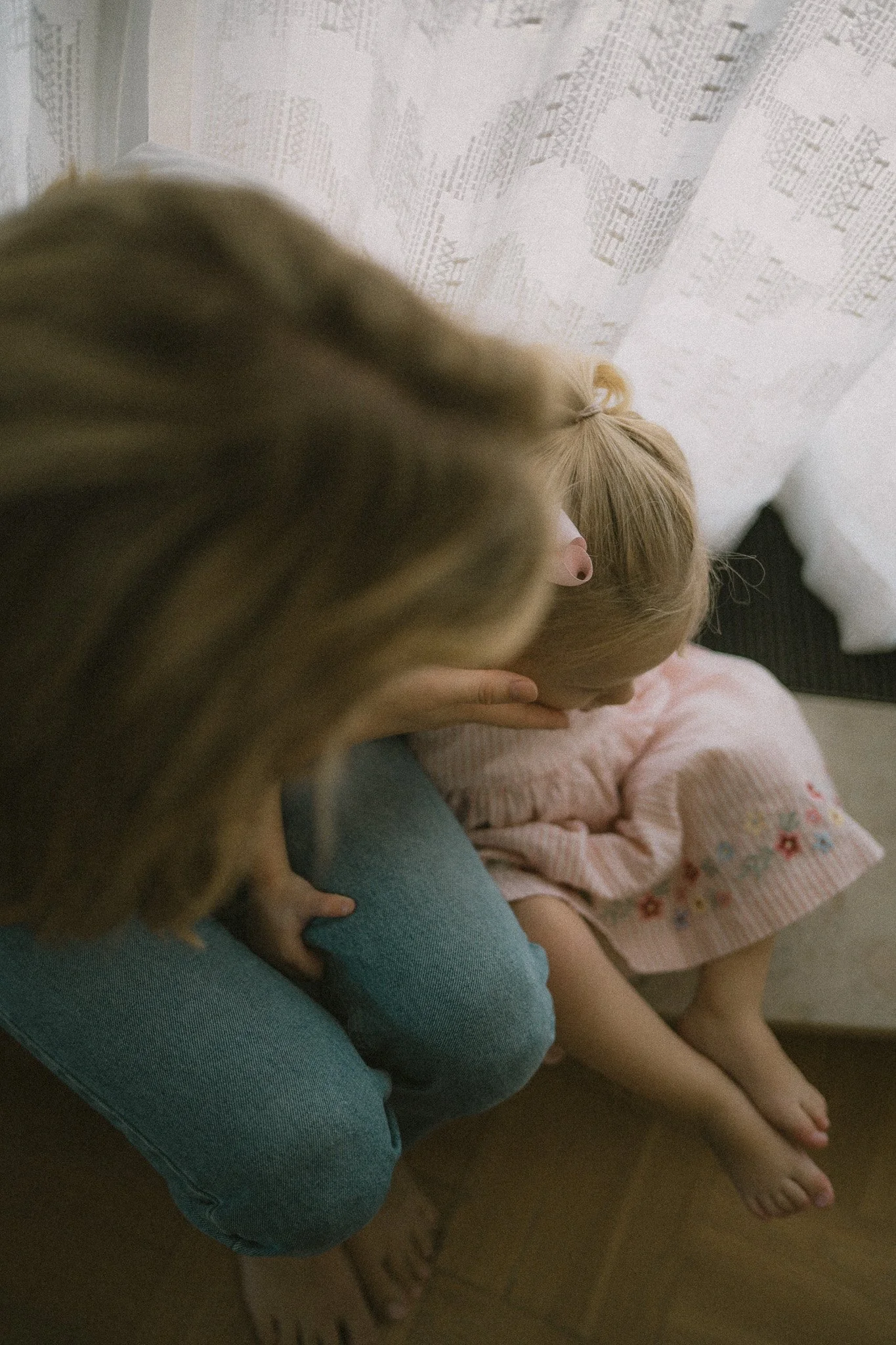 En kvinna som håller ett barn, som sitter på en soffa.