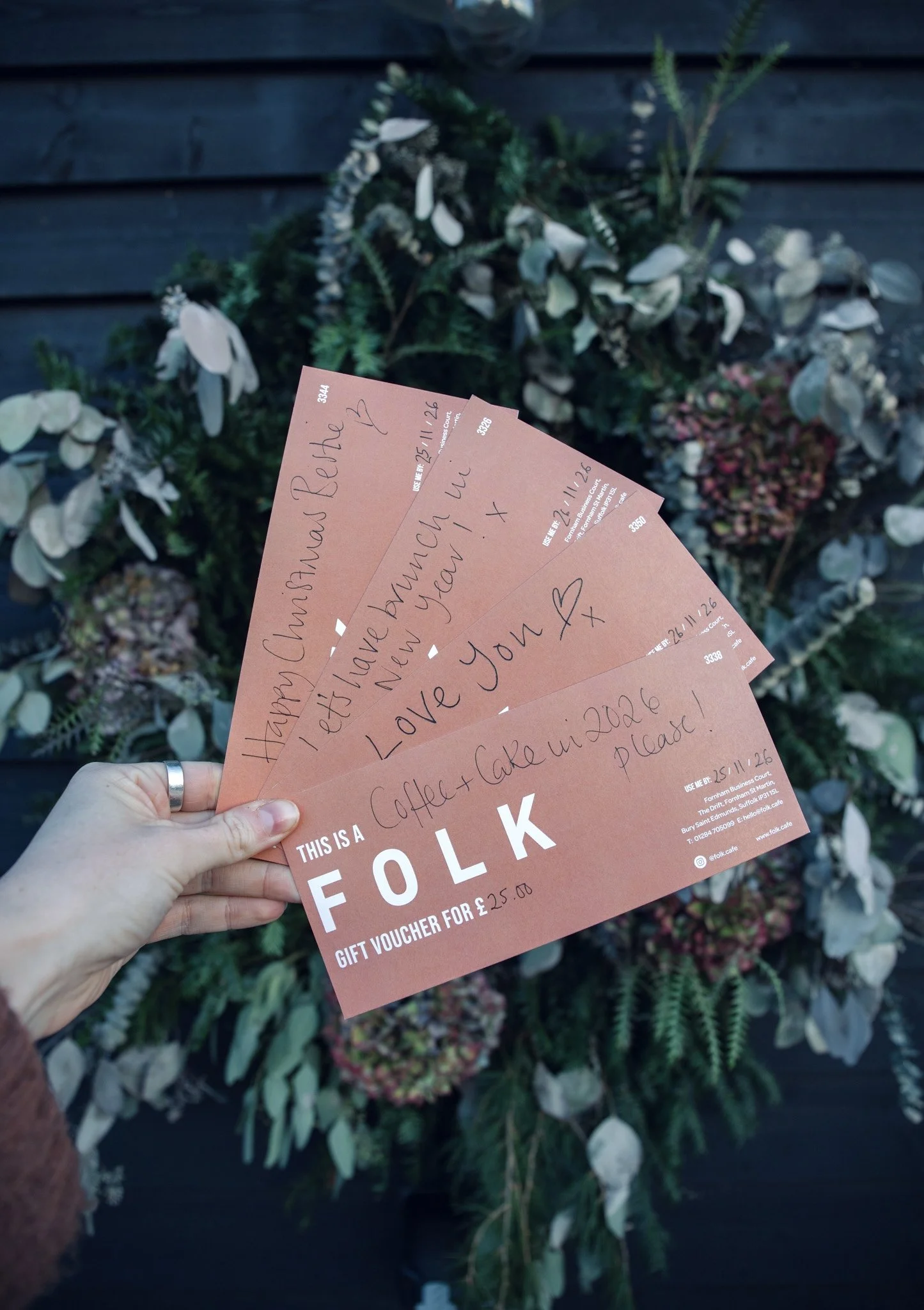 Gift voucher labeled 'Folk' for £30, partially inside a brown envelope, on a wooden surface.