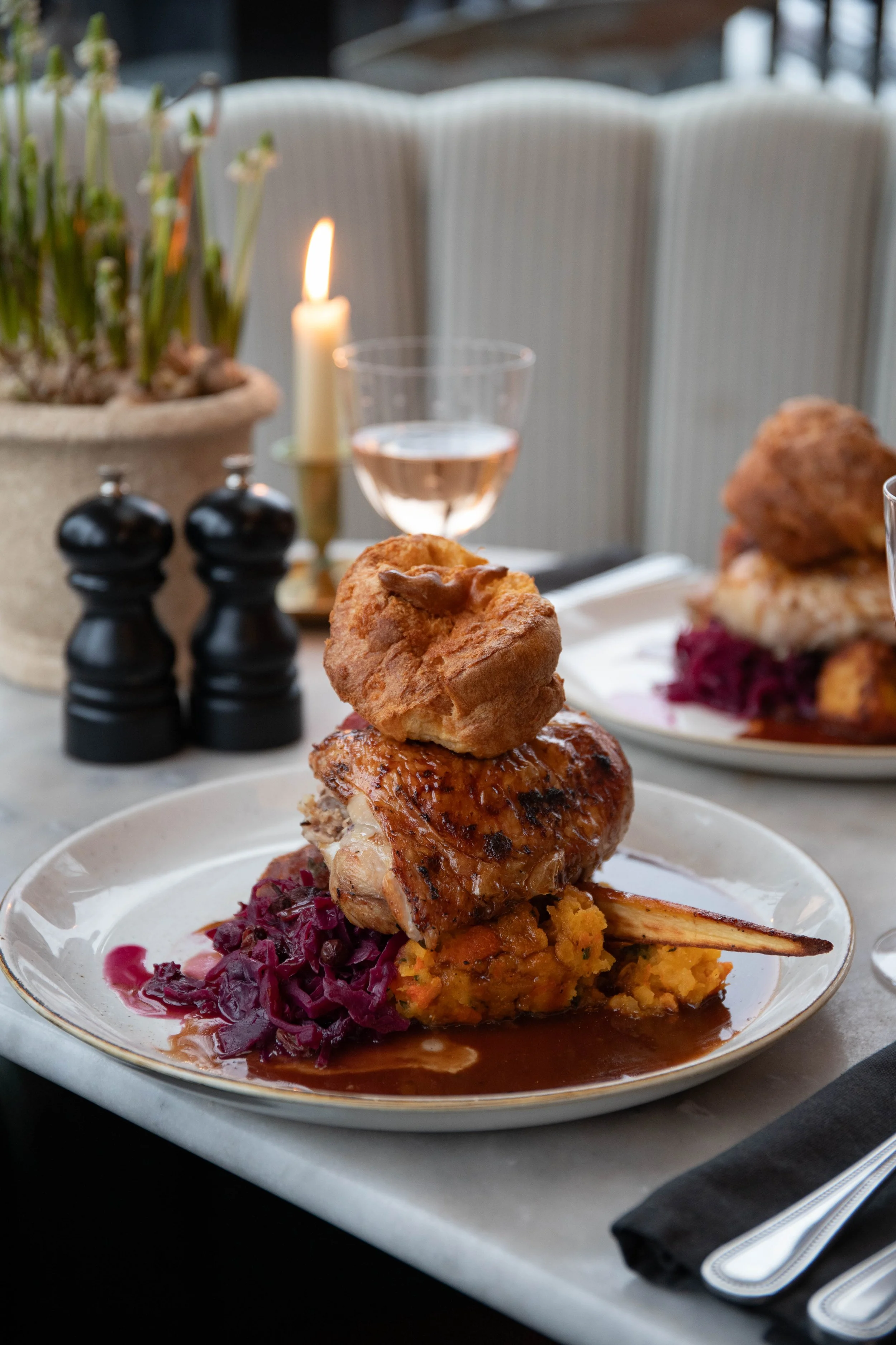 Various metallic jewelry pieces, including rings, charms, and pendants, laid out on a white surface with sunlight casting shadows.