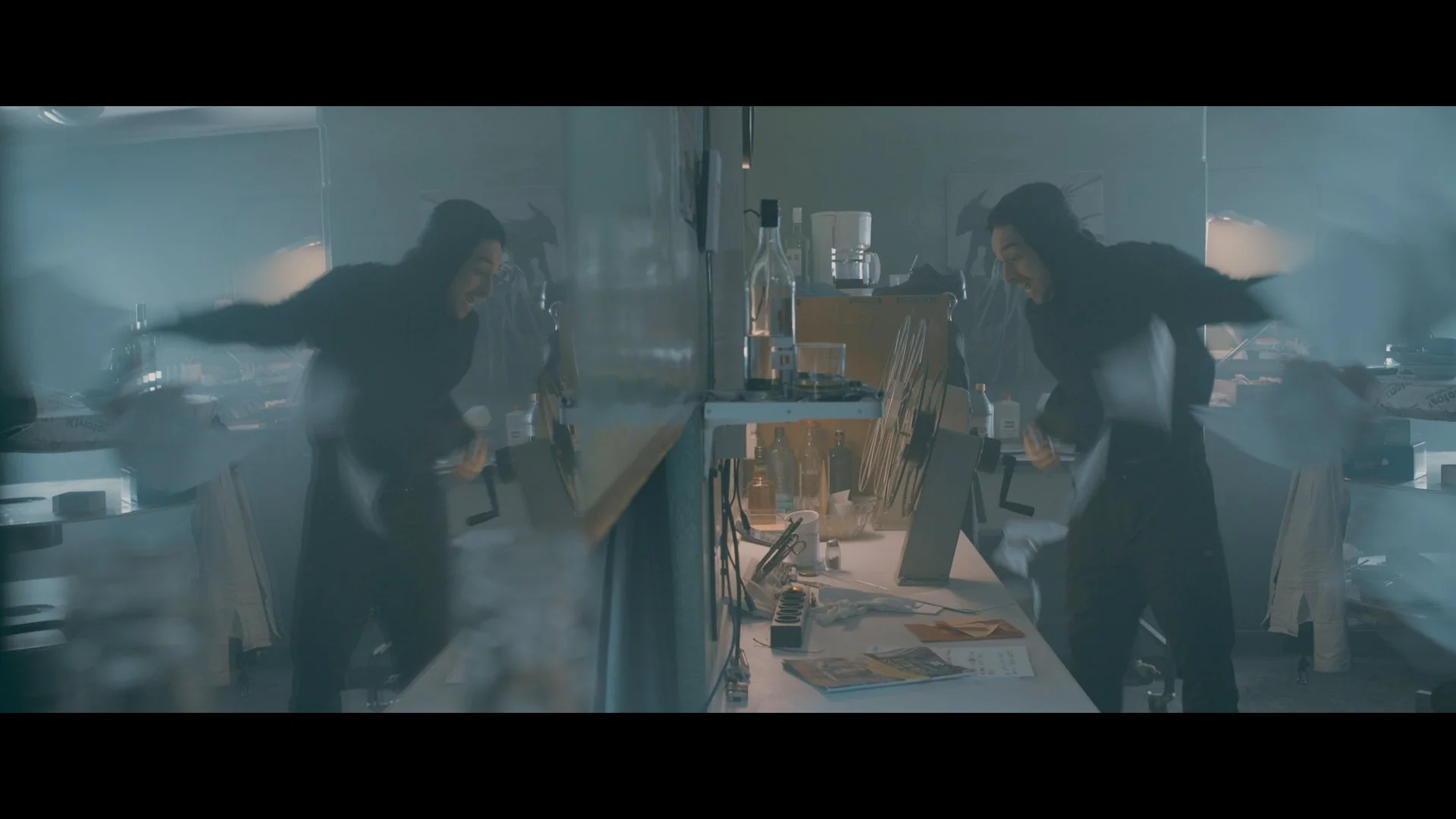 Zwei Frauen in einem chaotischen Labor umarmen sich und lachen, während Rauch und Chaos um sie herum herrschen.